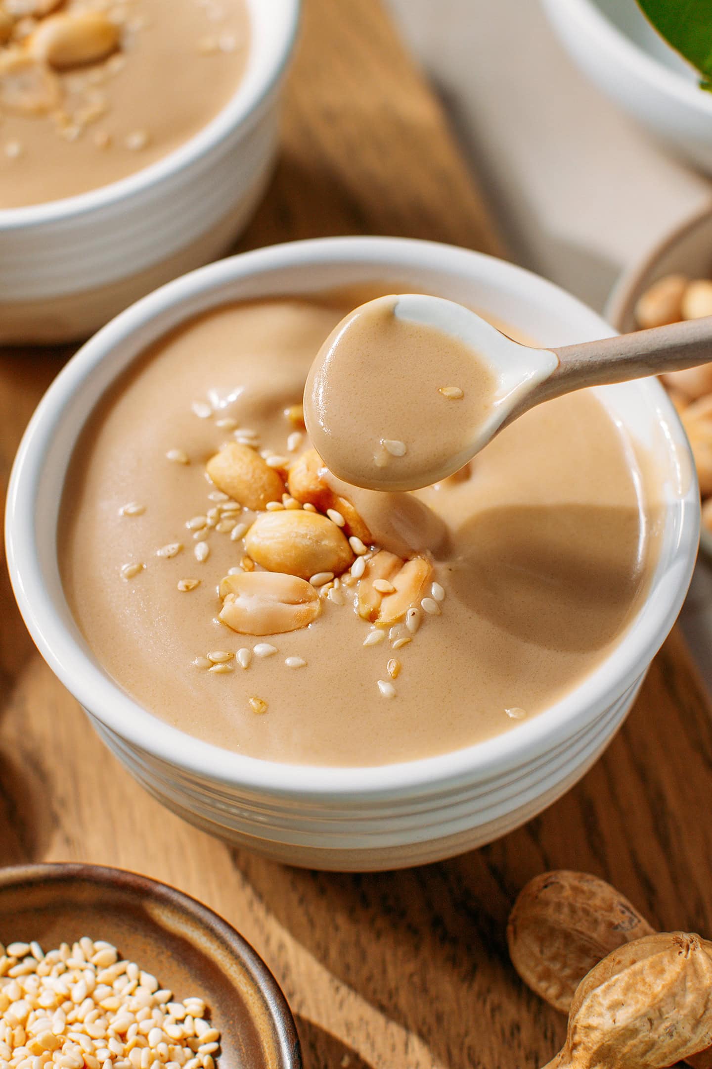Spoonful of sweet peanut soup over a bowl.