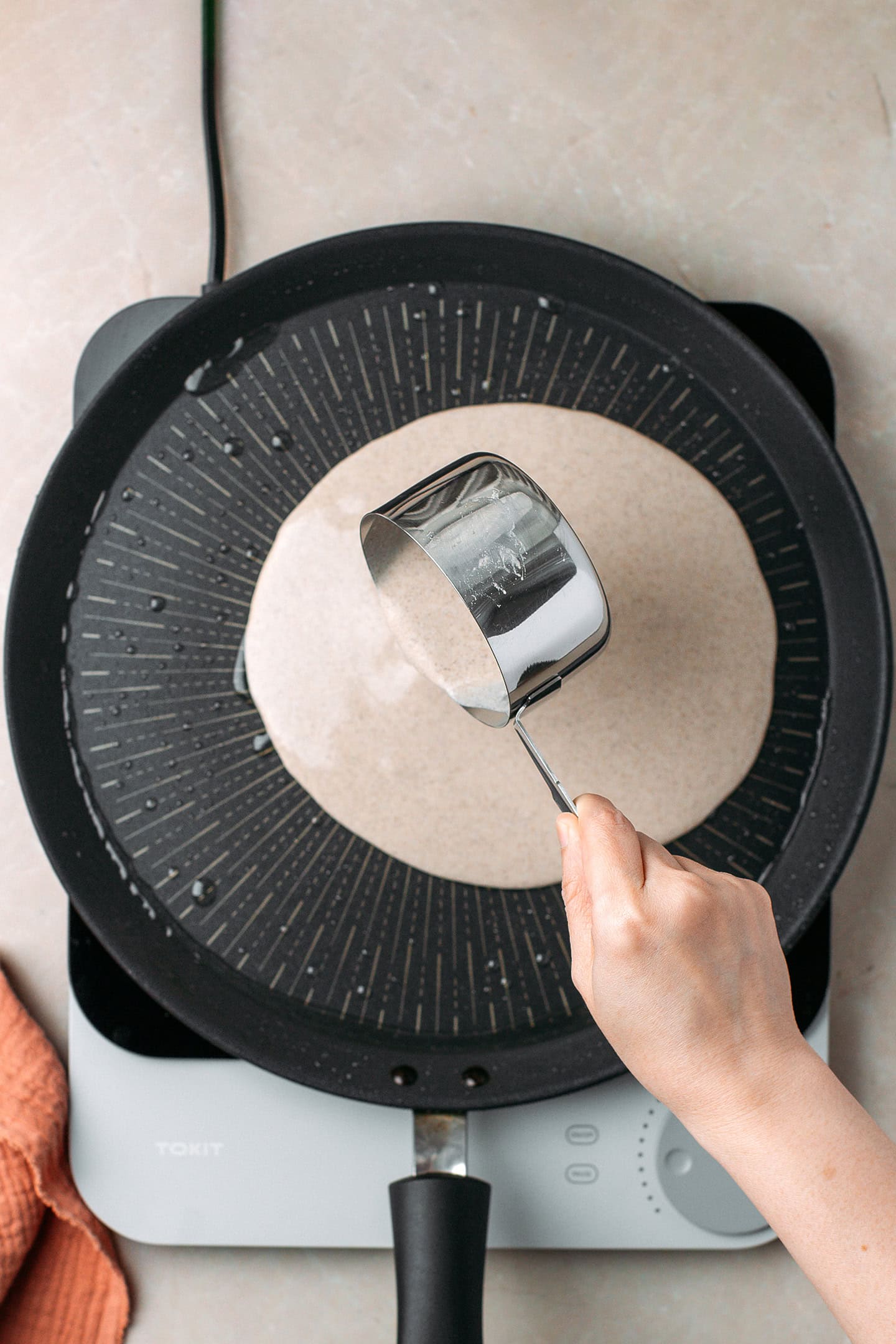Pouring buckwheat crêpe batter into a non-stick skillet.