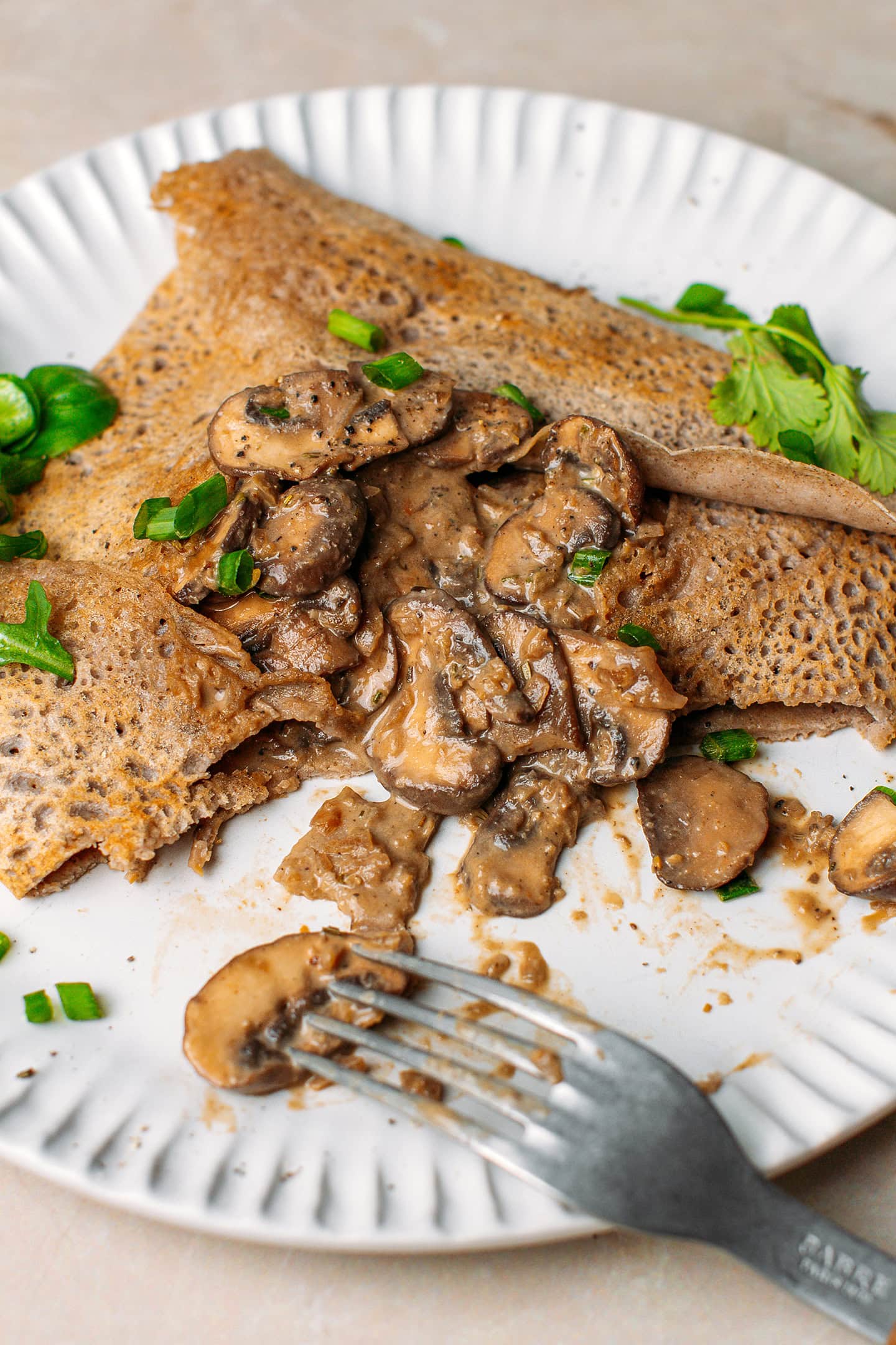 Close-up of a buckwheat crêpe filled with a creamy filling of sautéed mushrooms.