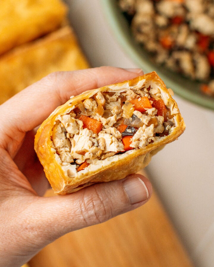 Holding a piece of fried tofu stuffed with vegetables.