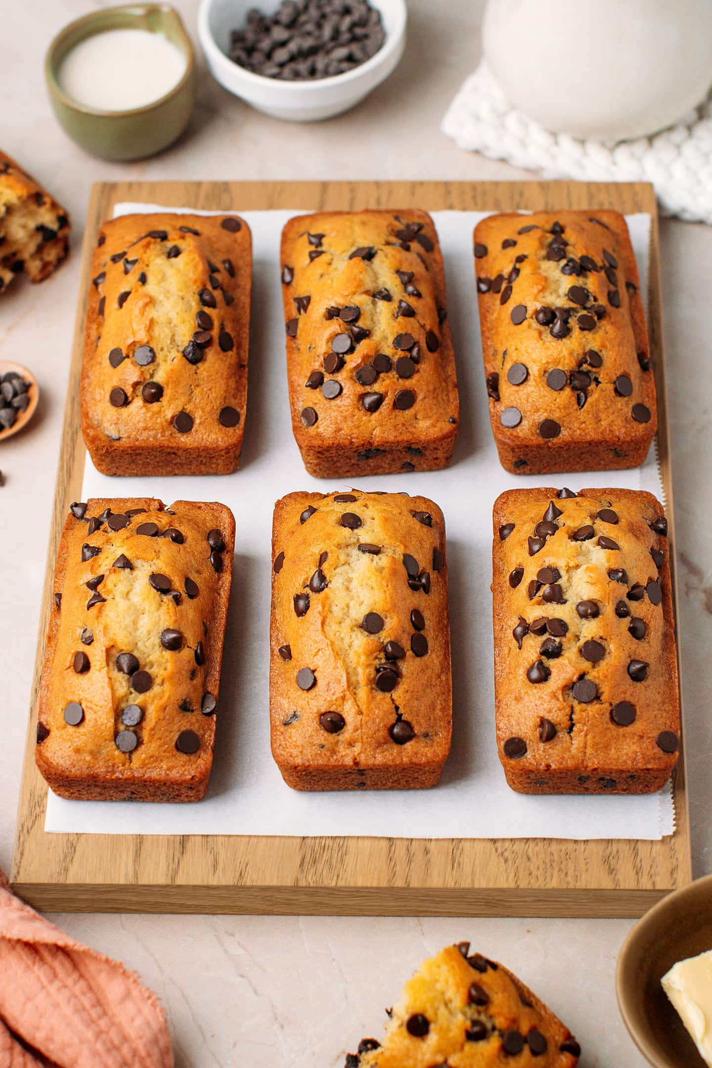 Six mini chocolate chip loaf cakes on a wooden cutting board.