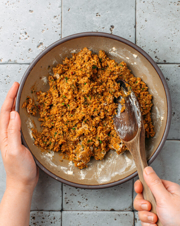 Mixing processed TVP chunks with vital wheat gluten in a bowl.