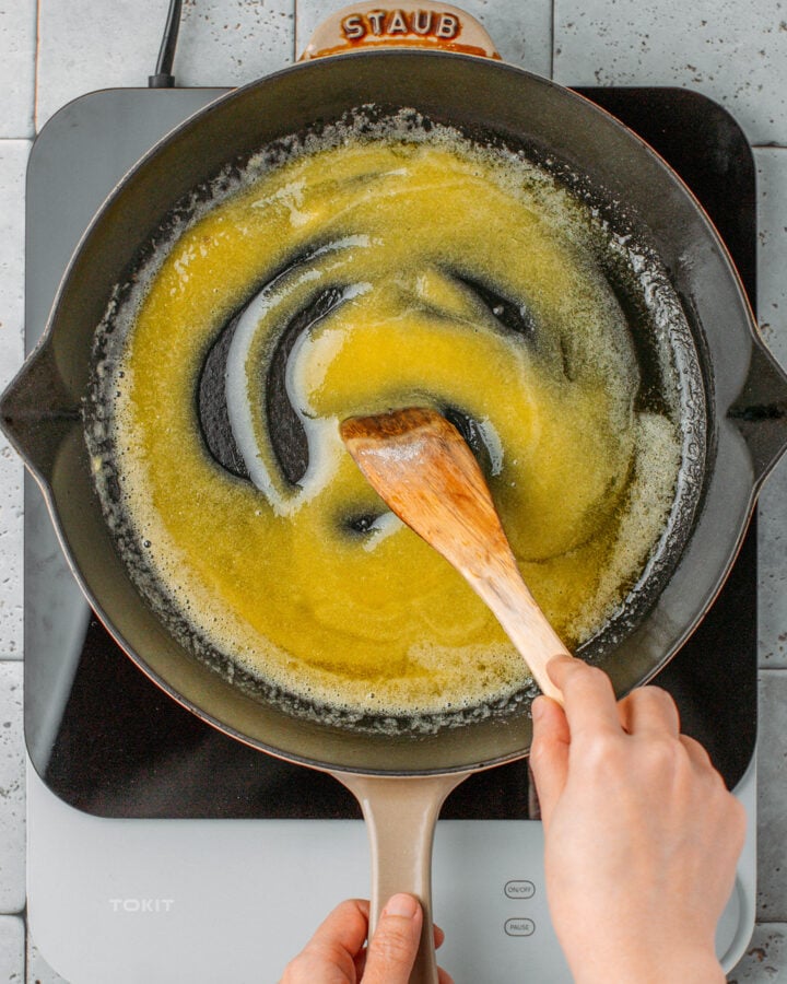 Stirring flour with melted butter in a skillet.