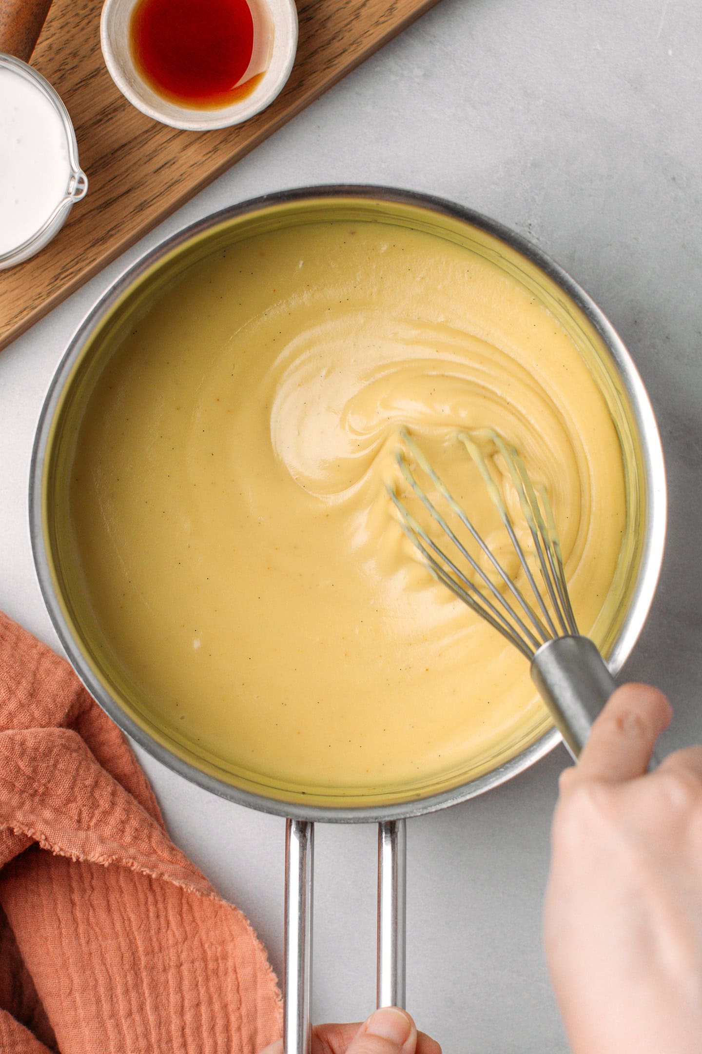 Whisking vanilla custard inside a saucepan.