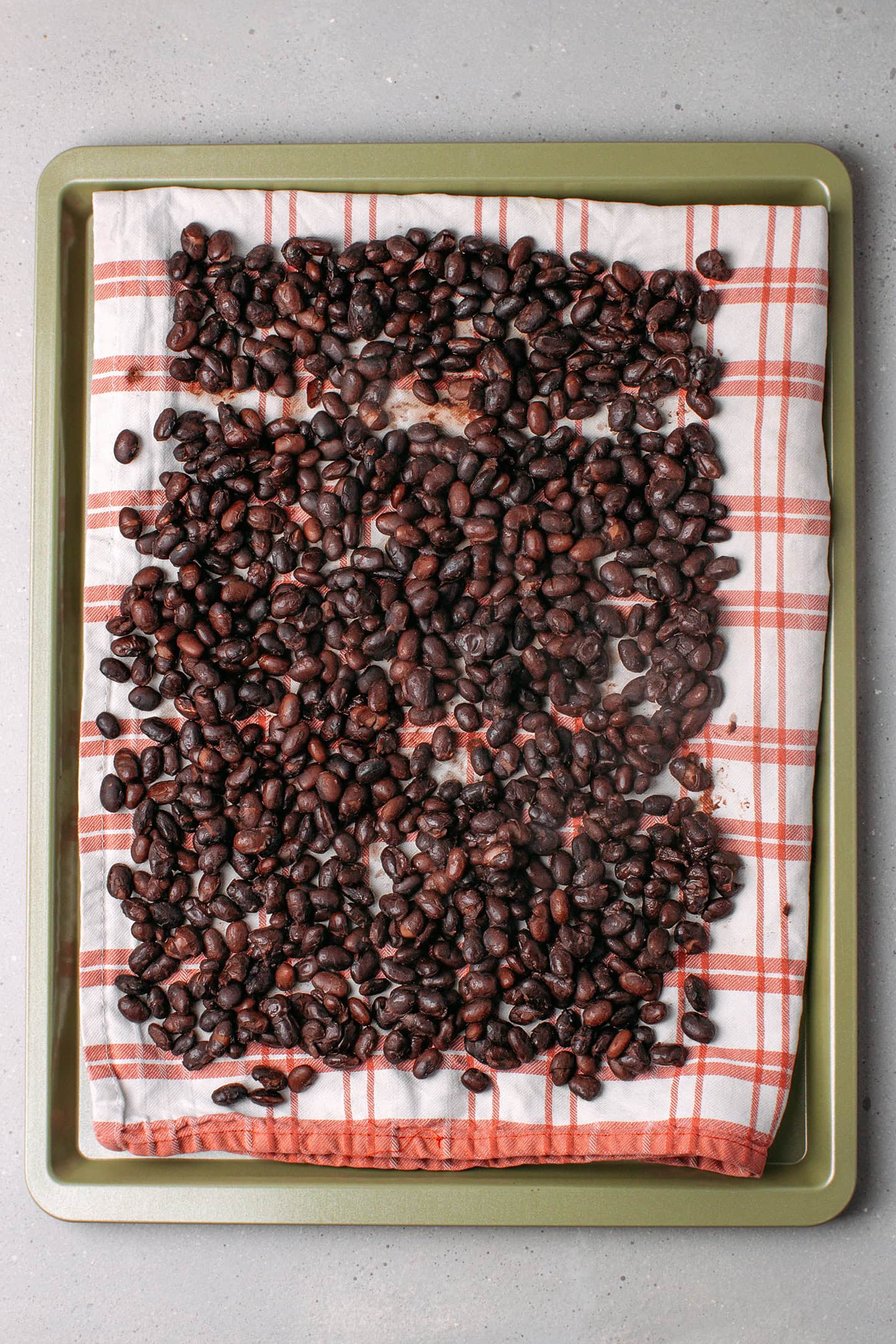 Cooked black beans spread on a kitchen towel.