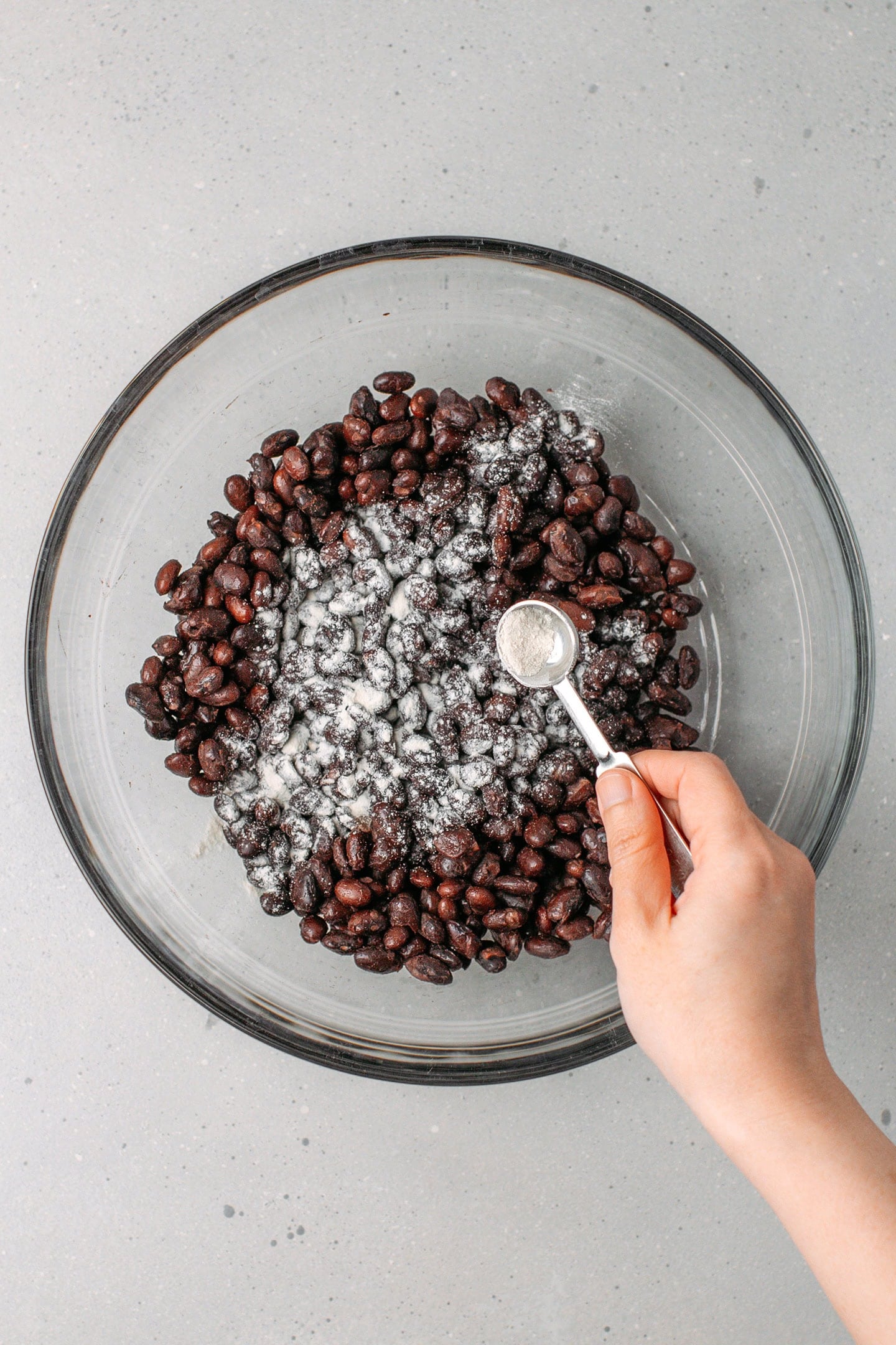 Sprinkling tempeh starter over cooked black beans.