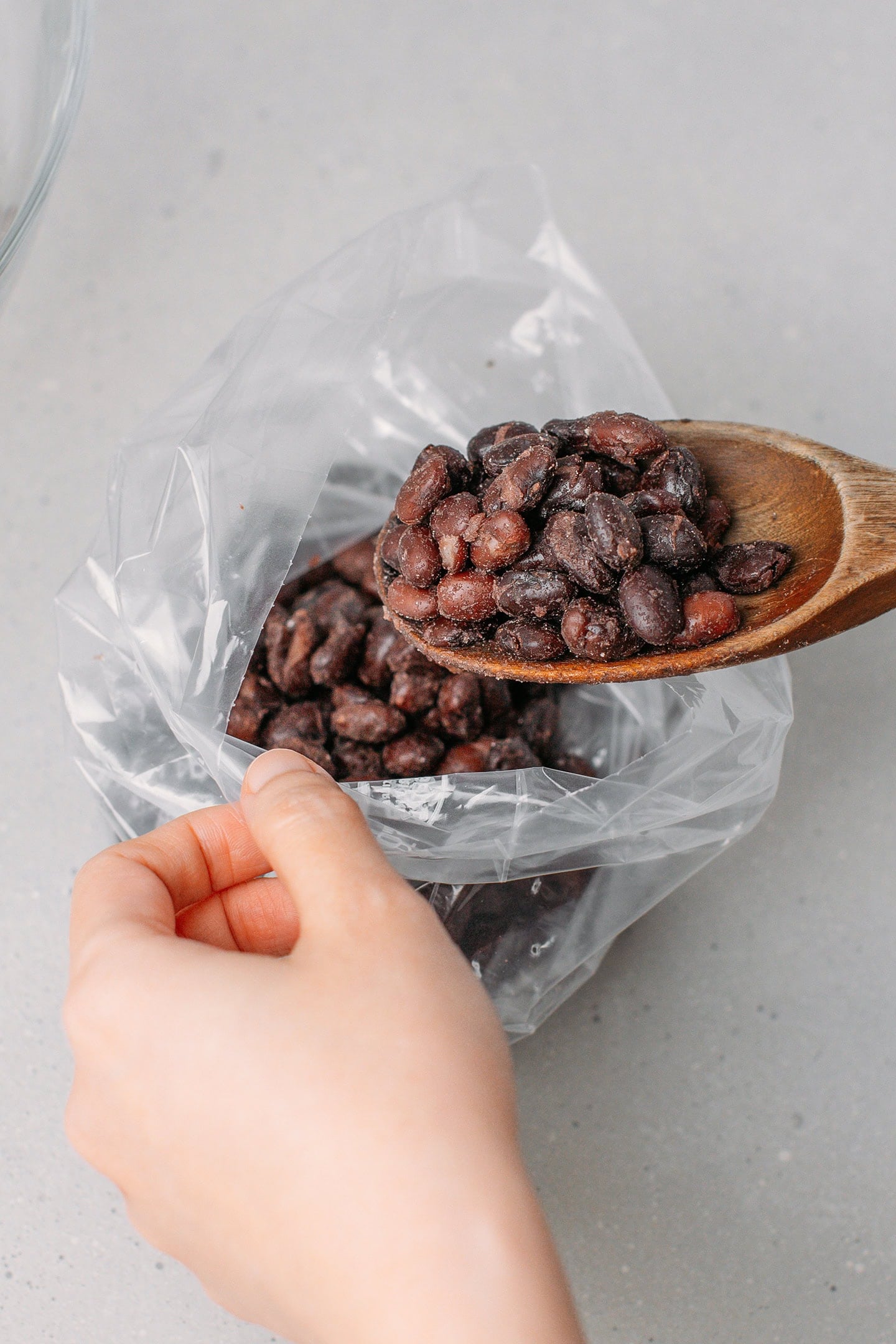Transferring cooked black beans to a freezer bag.