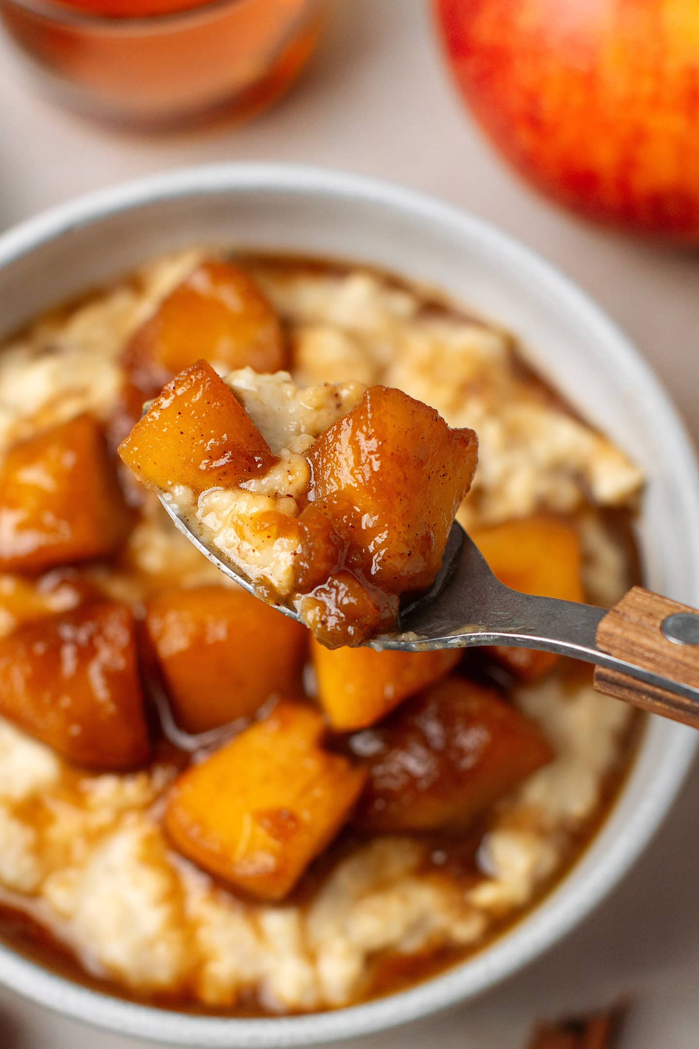 Close-up of a spoonful of cinnamon oatmeal topped with gooey apple chunks.
