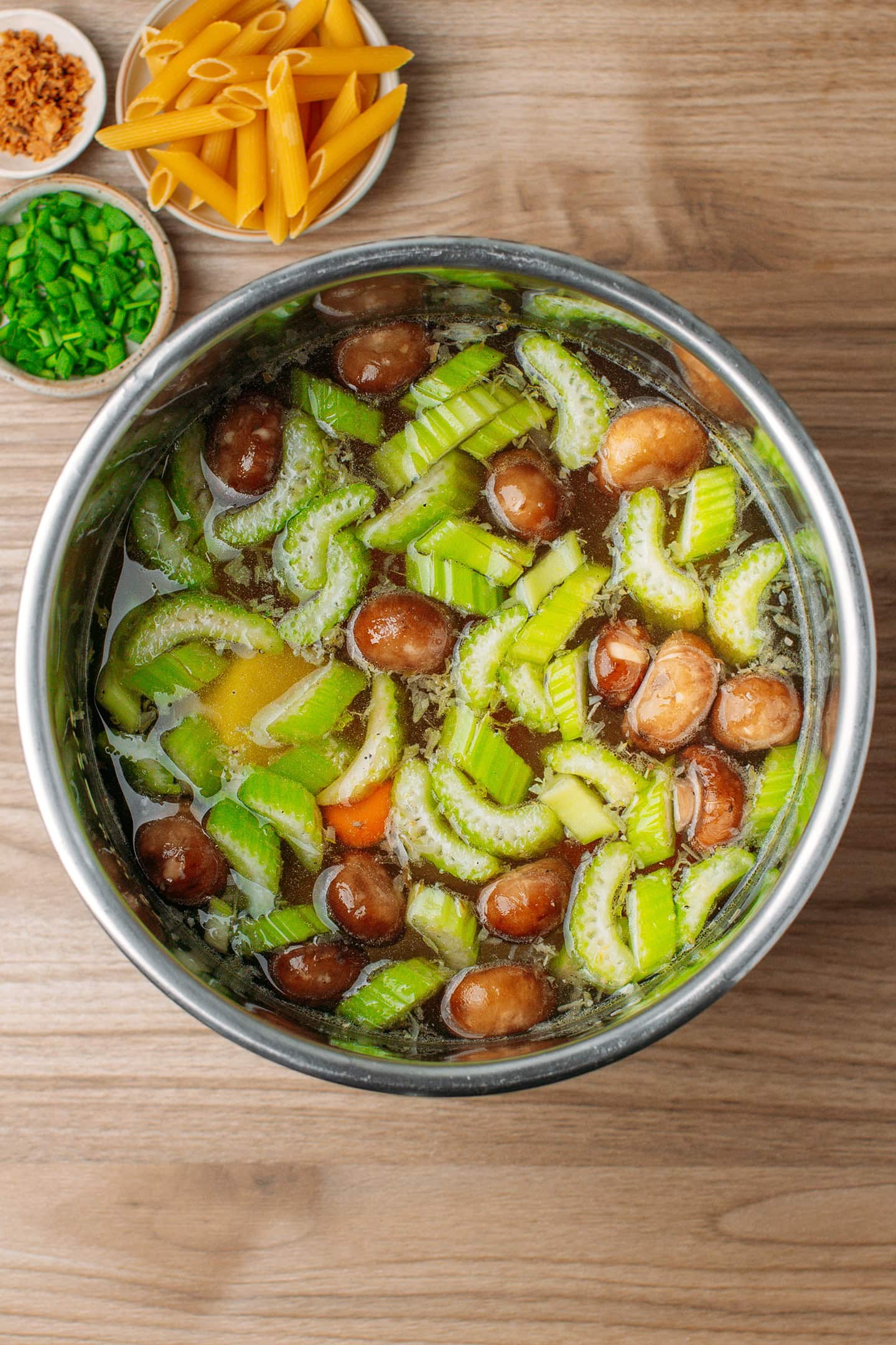 Pot of vegetable soup with celery, mushrooms, carrots, and potatoes.