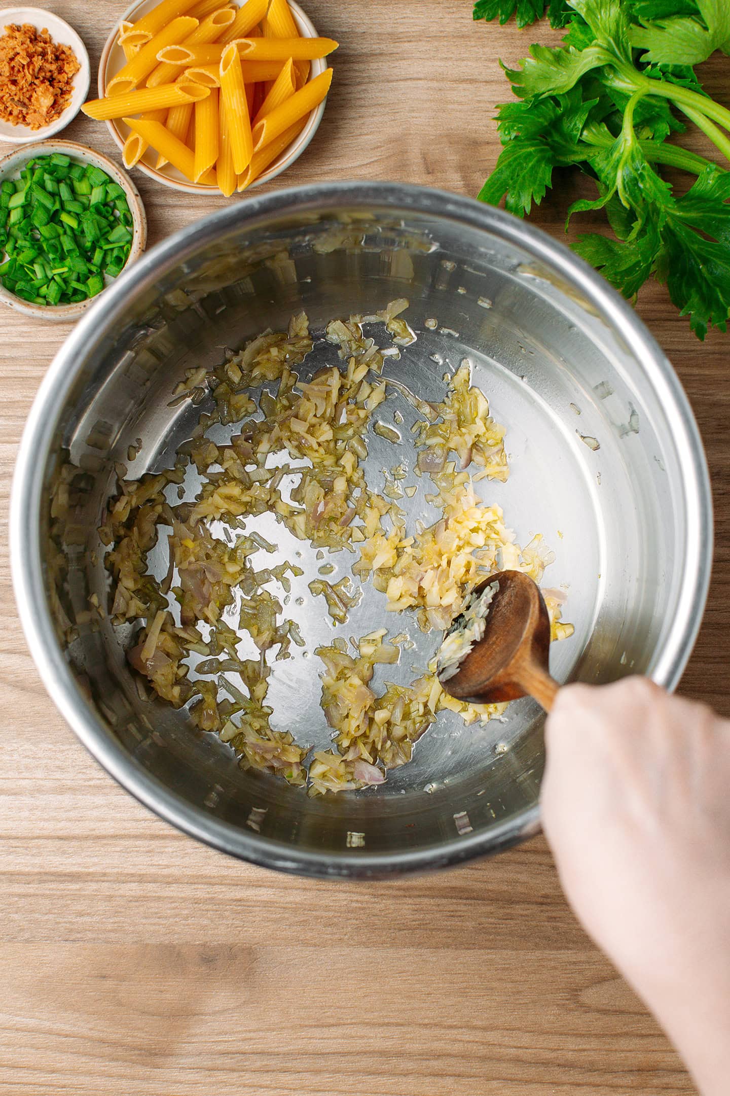 Stirring sautéed garlic and shallots in a pot.