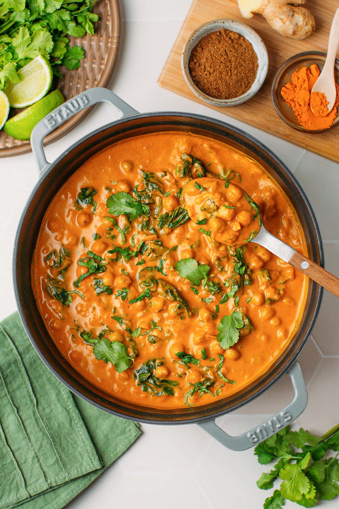 Creamy chickpea curry with spinach and chopped cilantro in a Dutch oven.