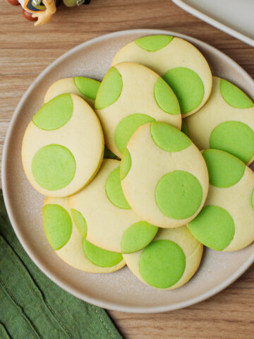 Plate filled with egg-shaped cookies with green dots.