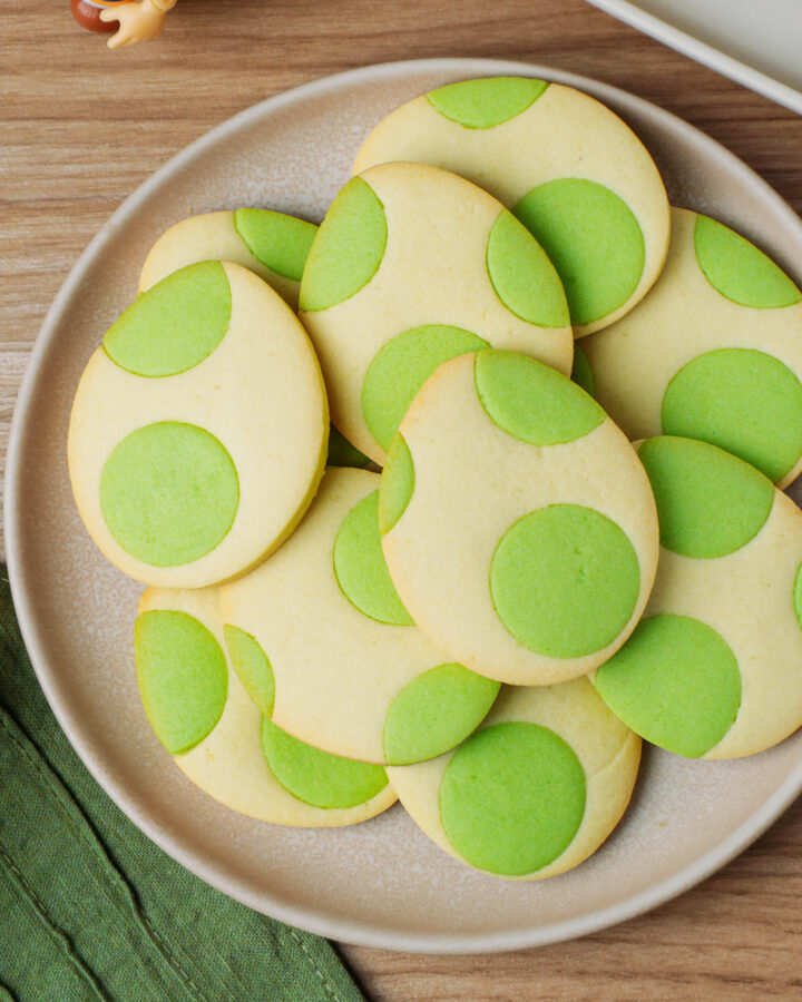 Plate filled with egg-shaped cookies with green dots.