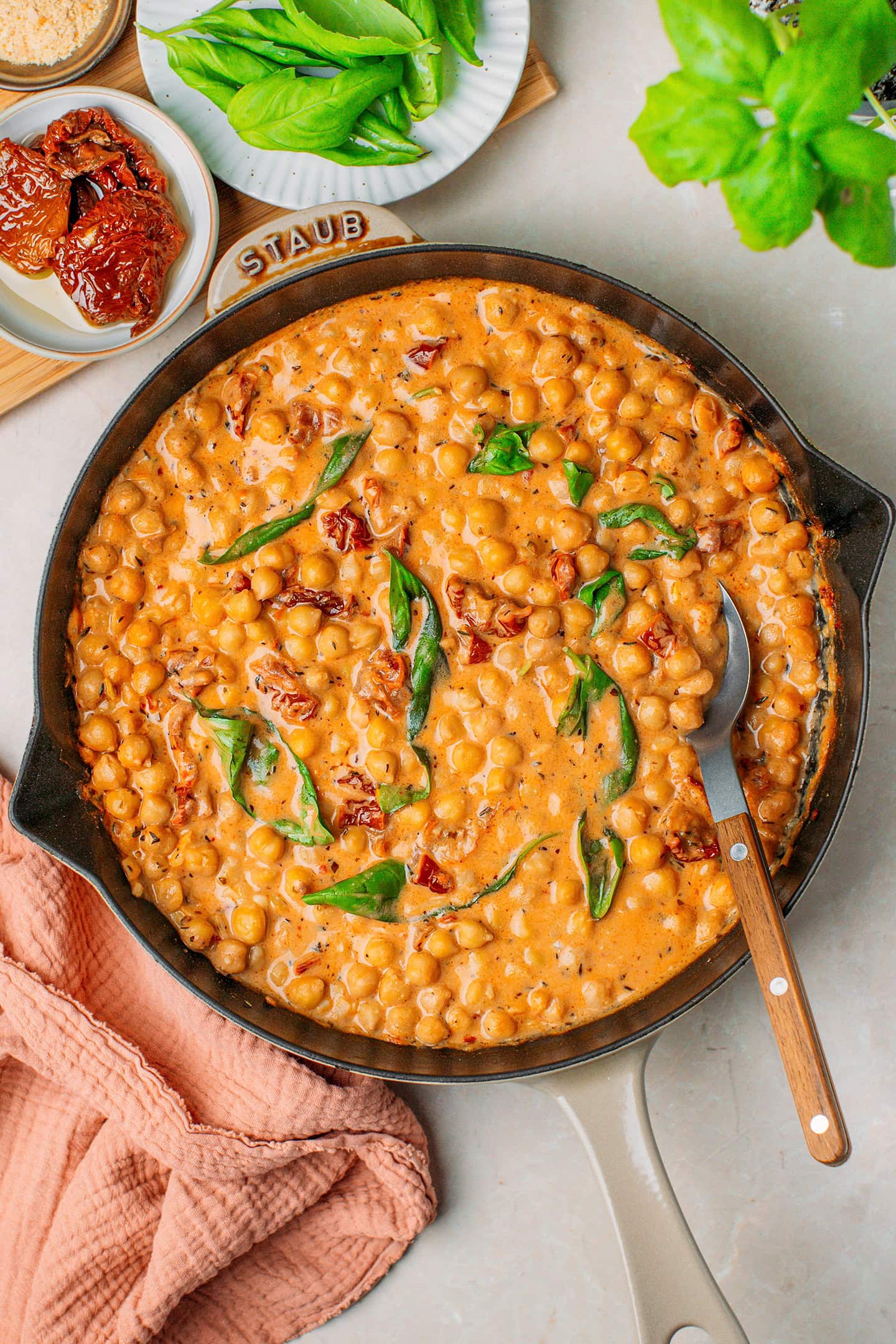 Chickpeas cooked in a Tuscan sauce with fresh basil in a skillet.