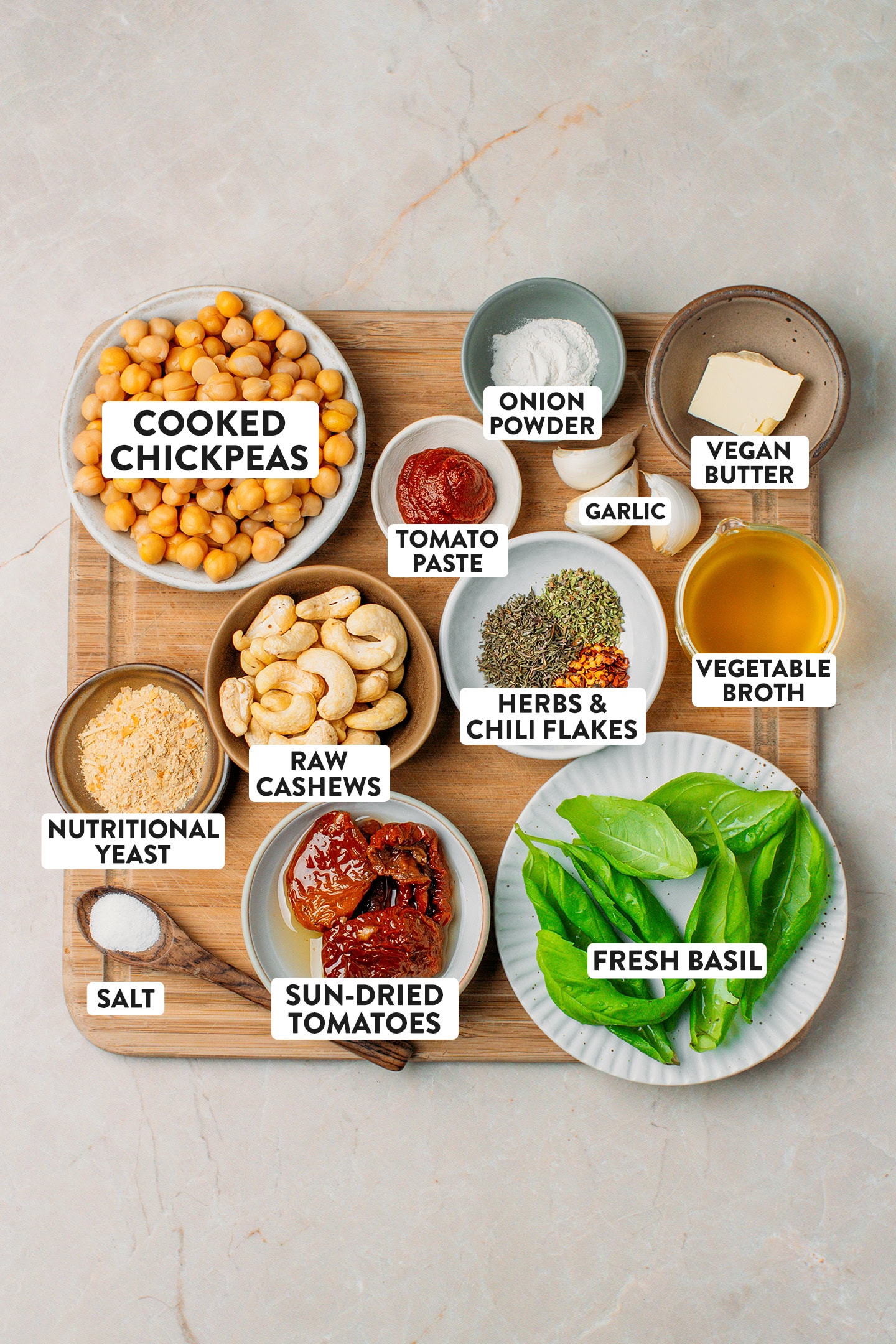 Ingredients like cooked chickpeas, sun-dried tomatoes, fresh basil, garlic, and cashews.