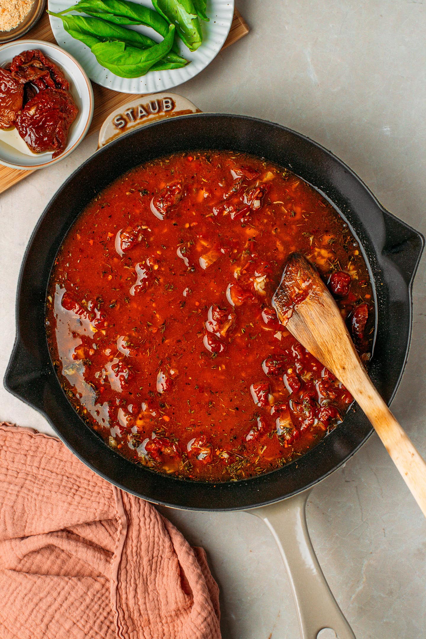Sautéed garlic, sun-dried tomatoes, dried herbs, and vegetable broth in a skillet.