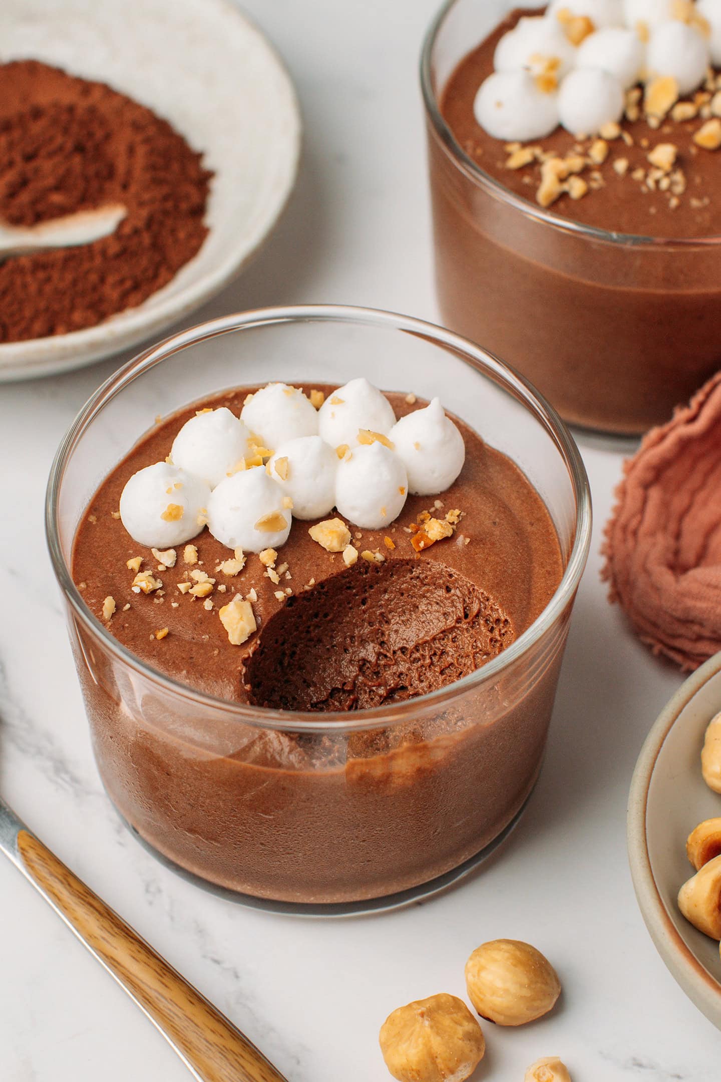 Chocolate hazelnut mousse topped with vegan whipping cream and crushed hazelnuts in a glass ramekin.
