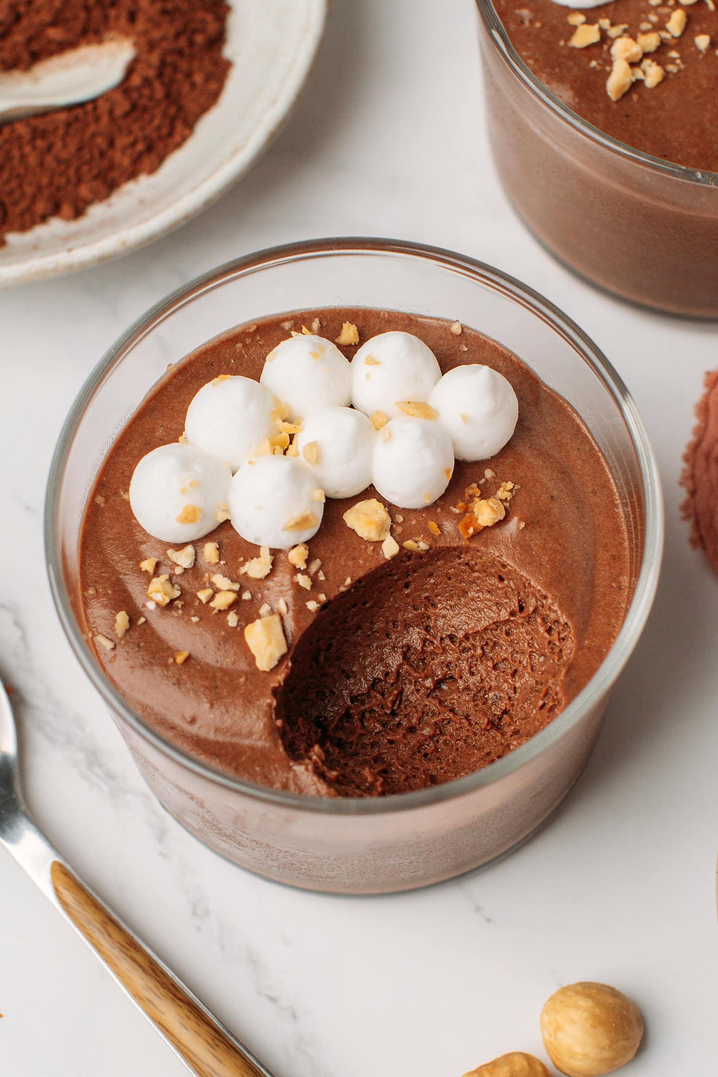 Chocolate hazelnut mousse topped with vegan whipping cream and crushed hazelnuts in a glass ramekin.