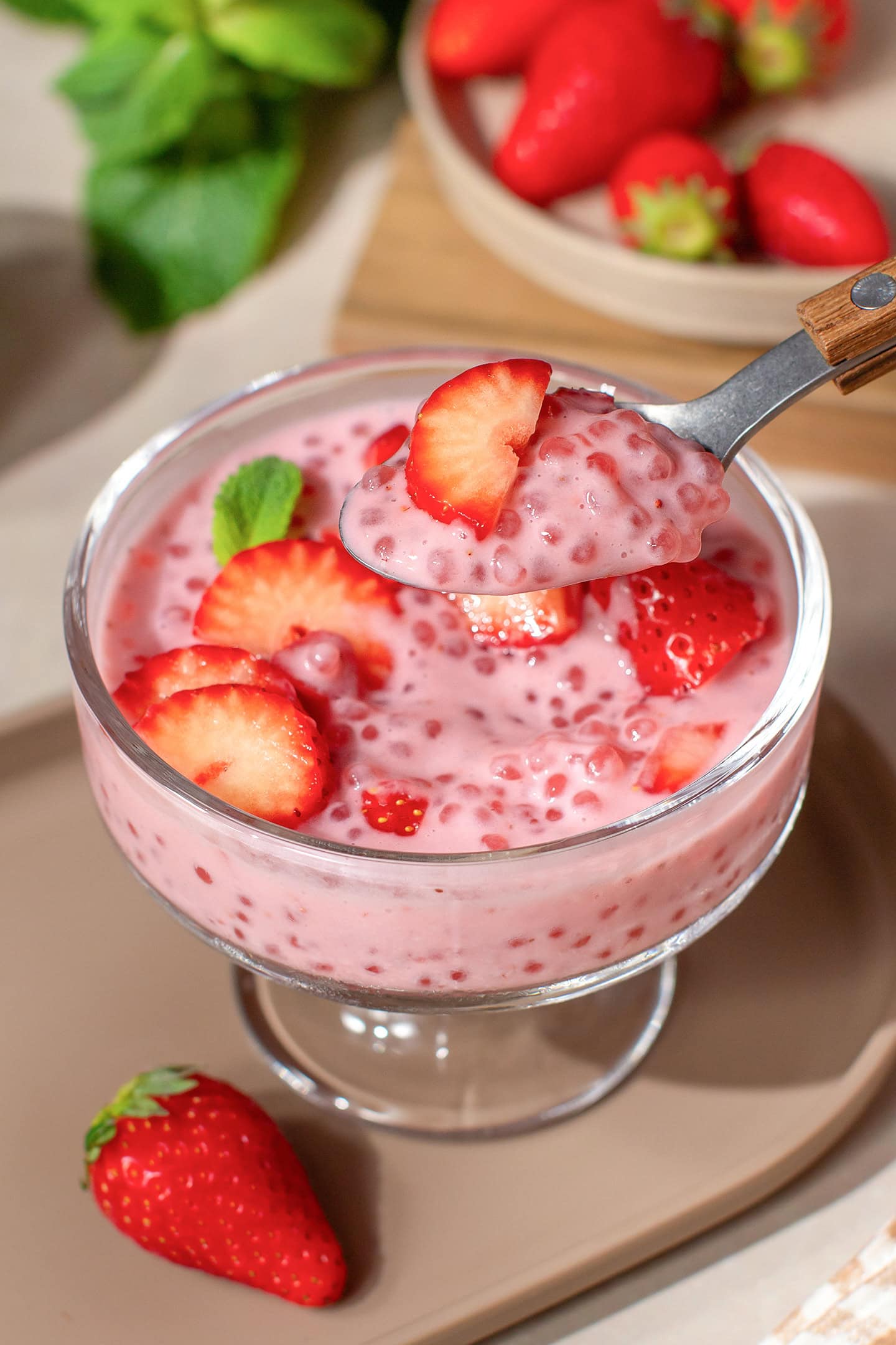 Spoonful of strawberry sago with sliced fresh strawberries.