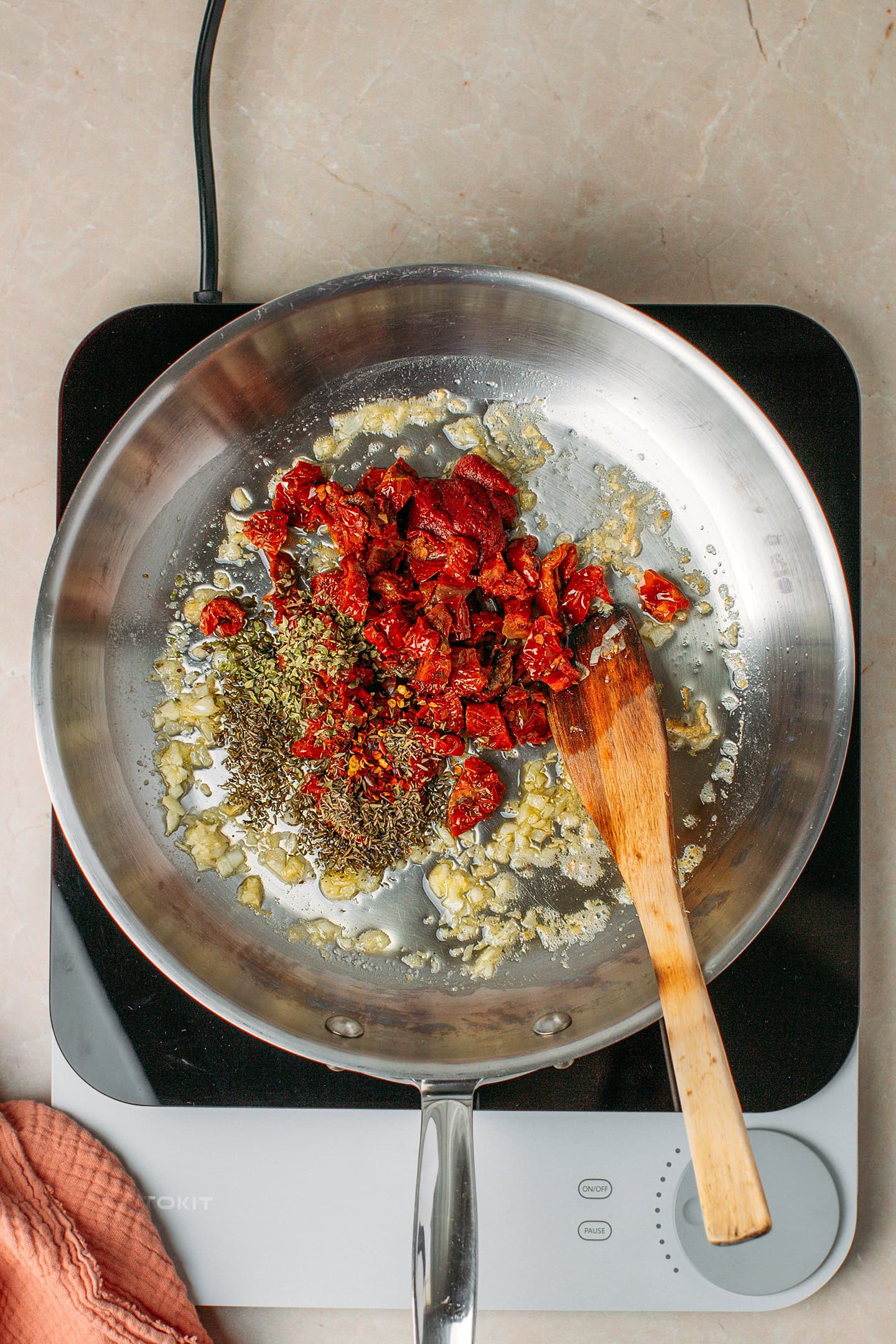 Sautéed garlic, chopped sun-dried tomatoes, and dried herbs in a skillet.