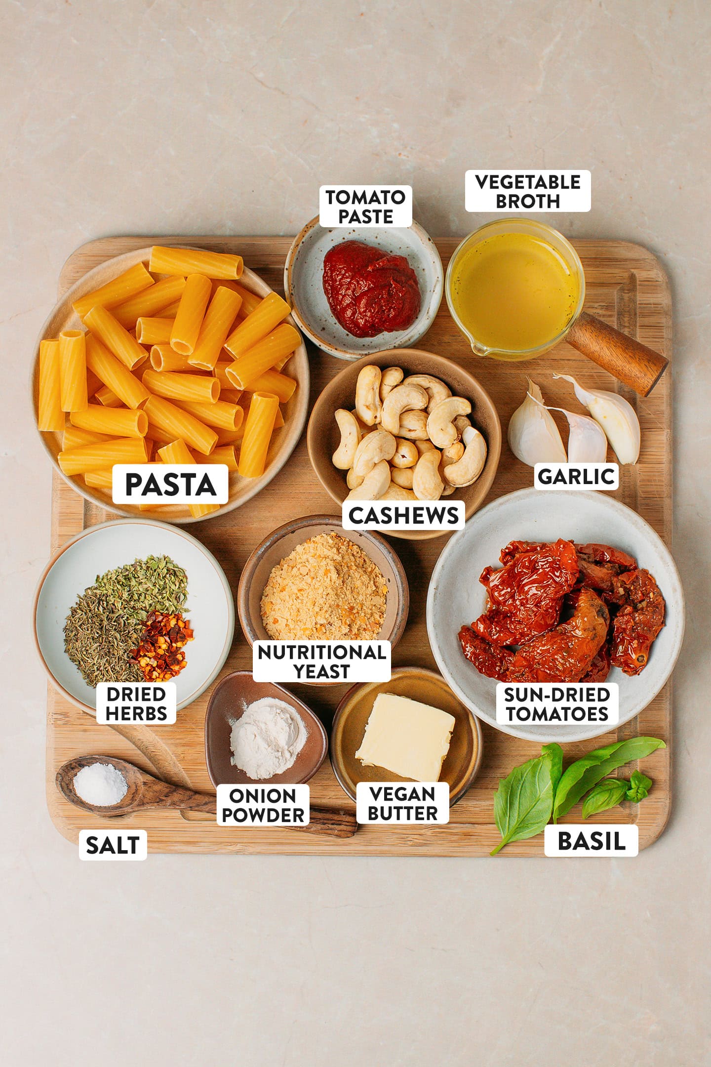 Ingredients like pasta, sun-dried tomatoes, cashews, nutritional yeast, and dried herbs.