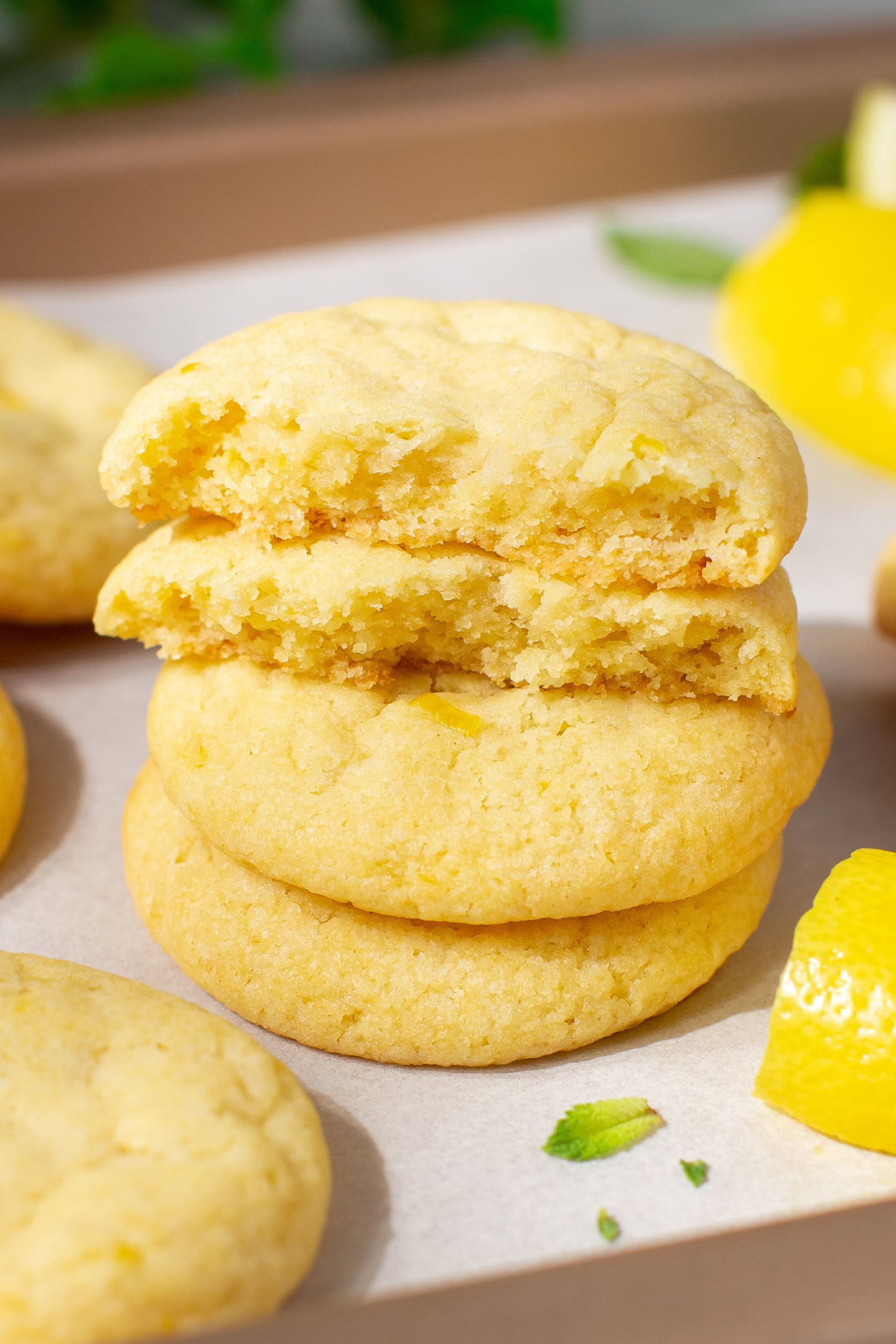 Chewy lemon cookies stacked on a baking sheet.