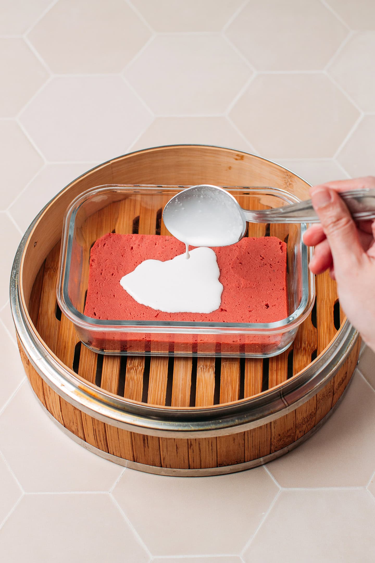 Pouring coconut milk mixture over a piece of seitan inside a baking dish.