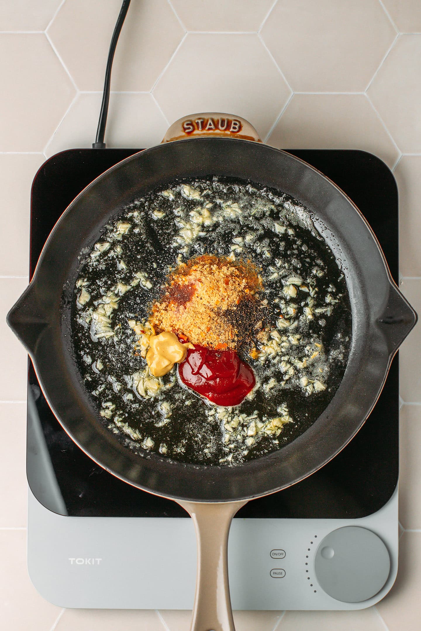 Sautéed garlic, nutritional yeast, ketchup, and mustard in a skillet.