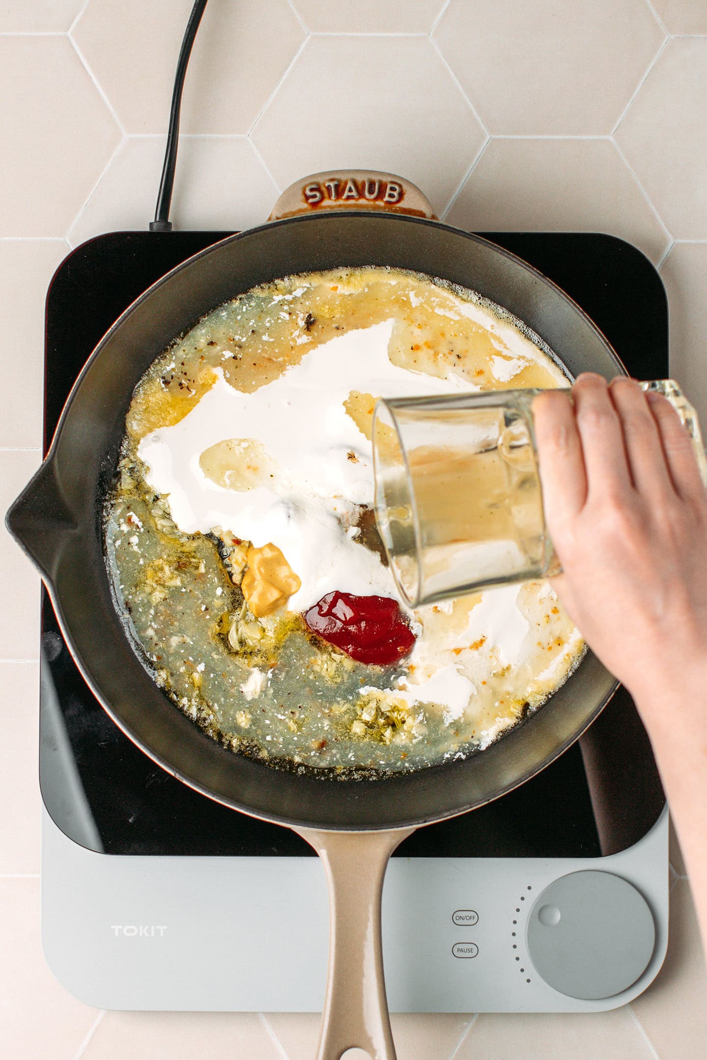 Pouring vegetable broth into a skillet.