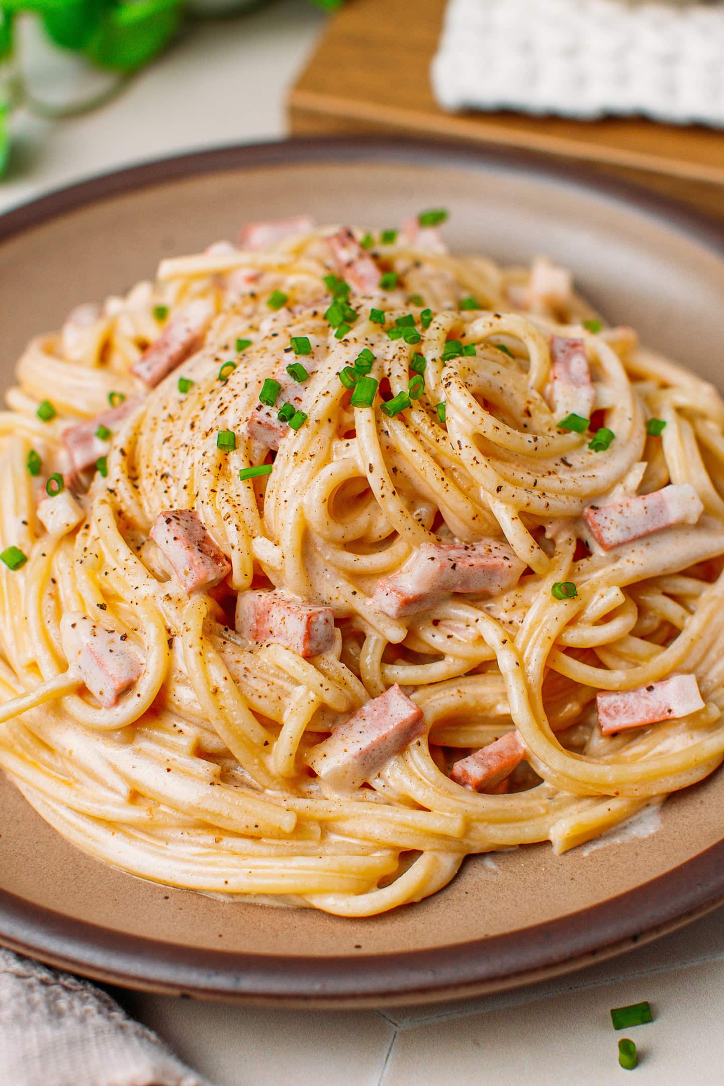 Close-up of creamy vegan carbonara with vegan bacon bits and chives.
