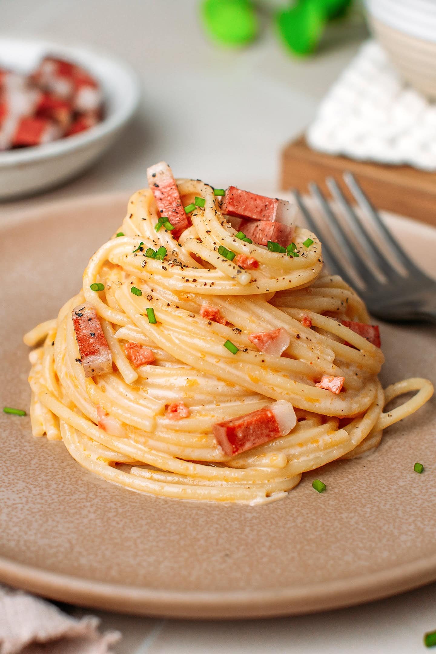 Nest of spaghetti coated with a carbonara sauce and combined with vegan bacon bits.