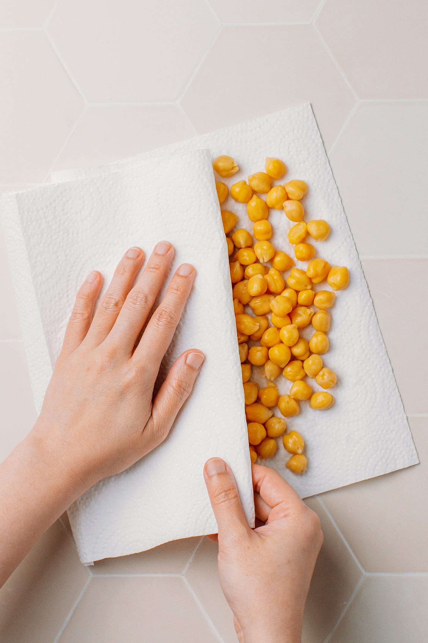 Patting chickpeas dry using kitchen paper towels.