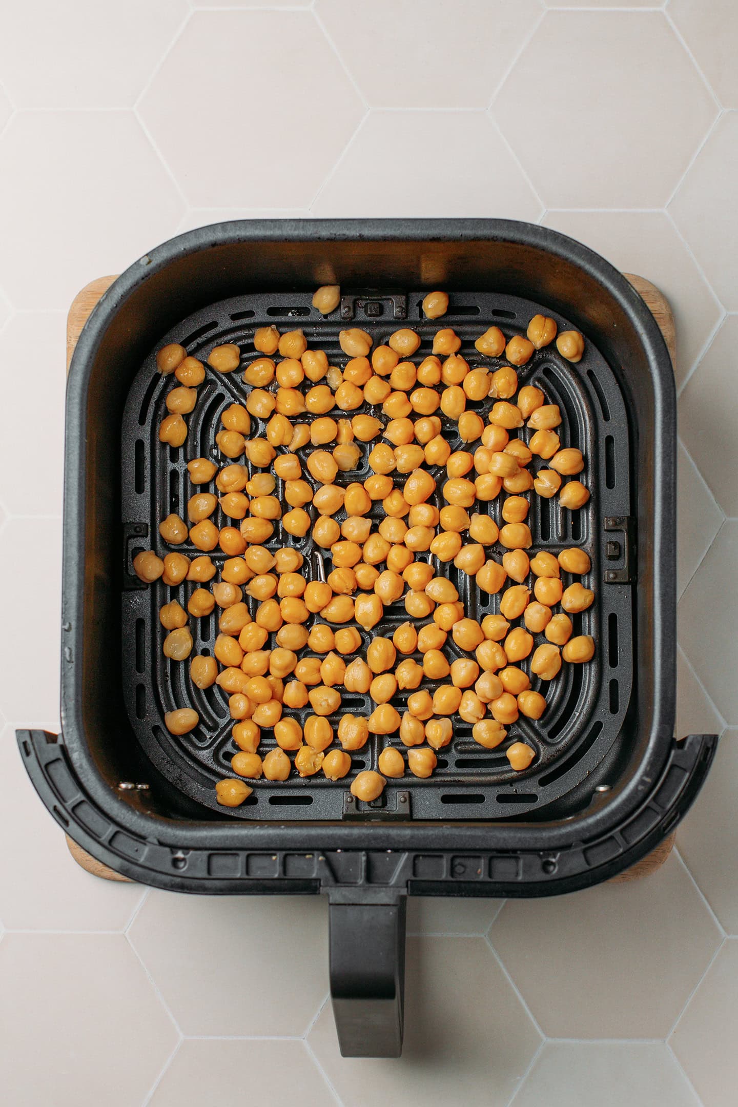 Cooked chickpeas in an air fryer basket.