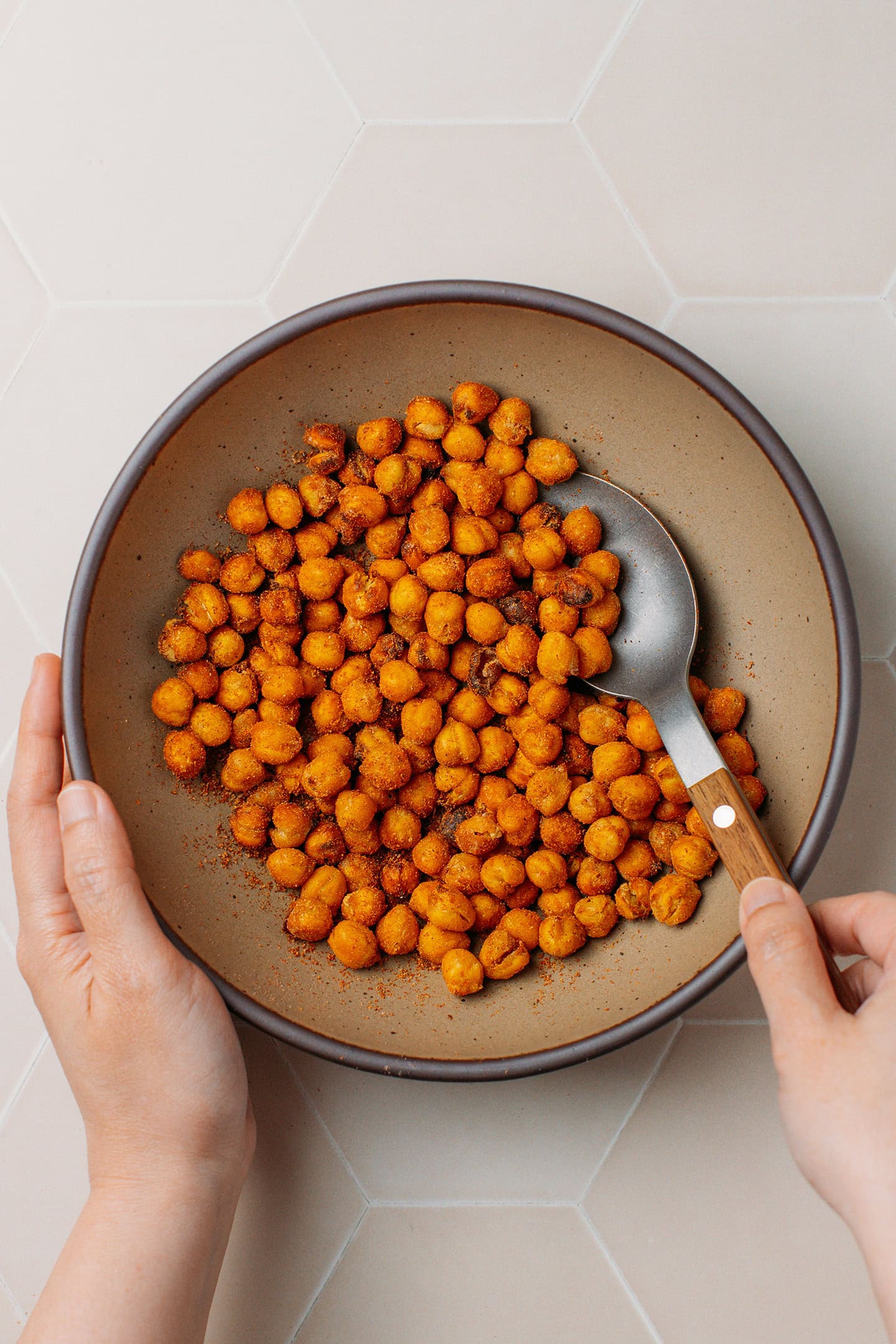 Tossing chickpeas with spices in a mixing bowl.