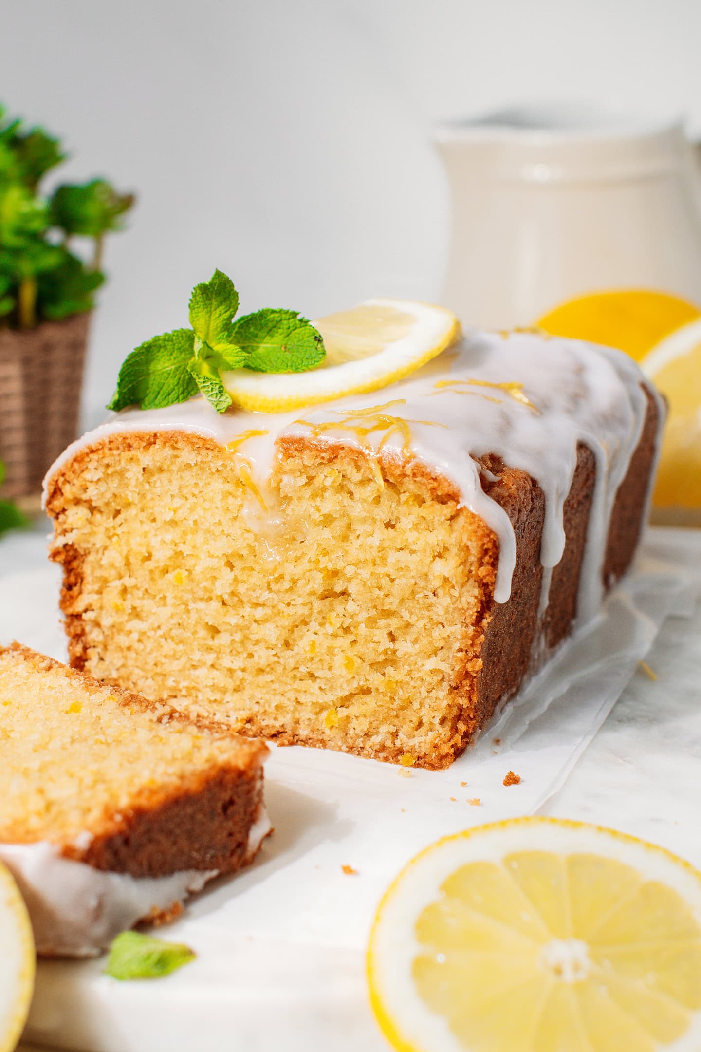 Sliced lemon loaf cake glazed with a lemon icing and topped with lemon zest.