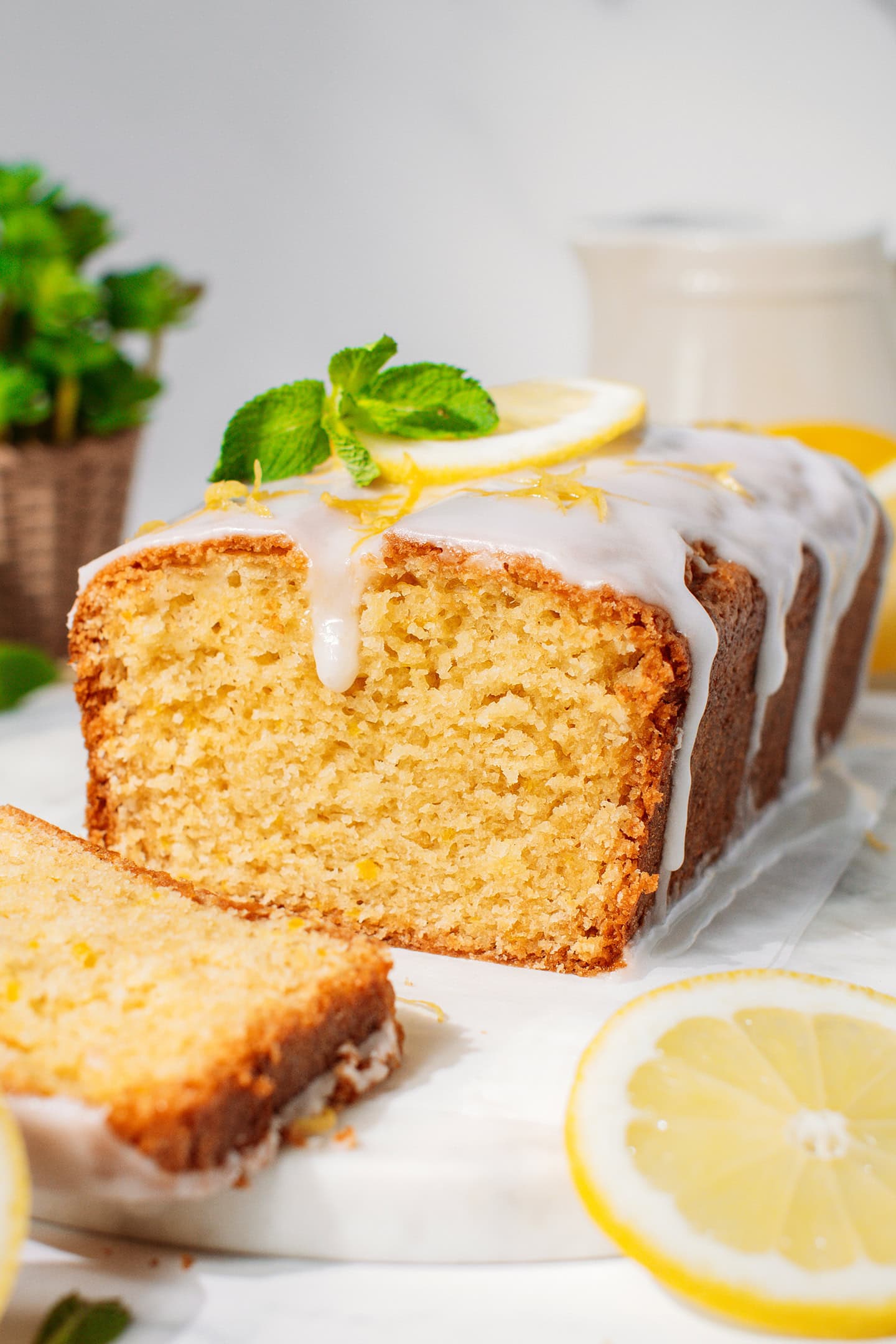 Lemon loaf cake glazed with lemon icing and topped with mint leaves.