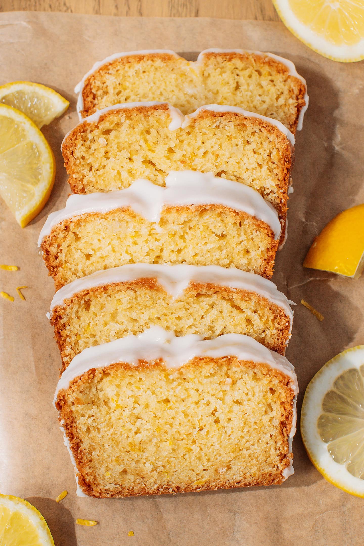 Five slices of lemon loaf cake on a layer of parchment paper.