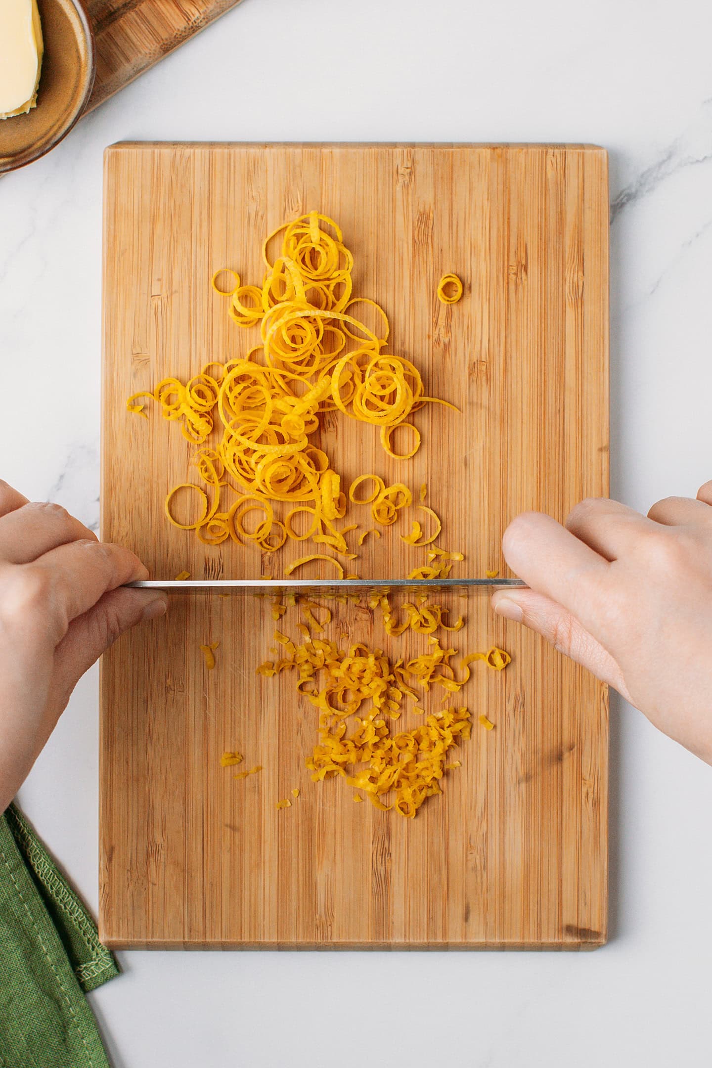 Chopping lemon zest on a cutting board.