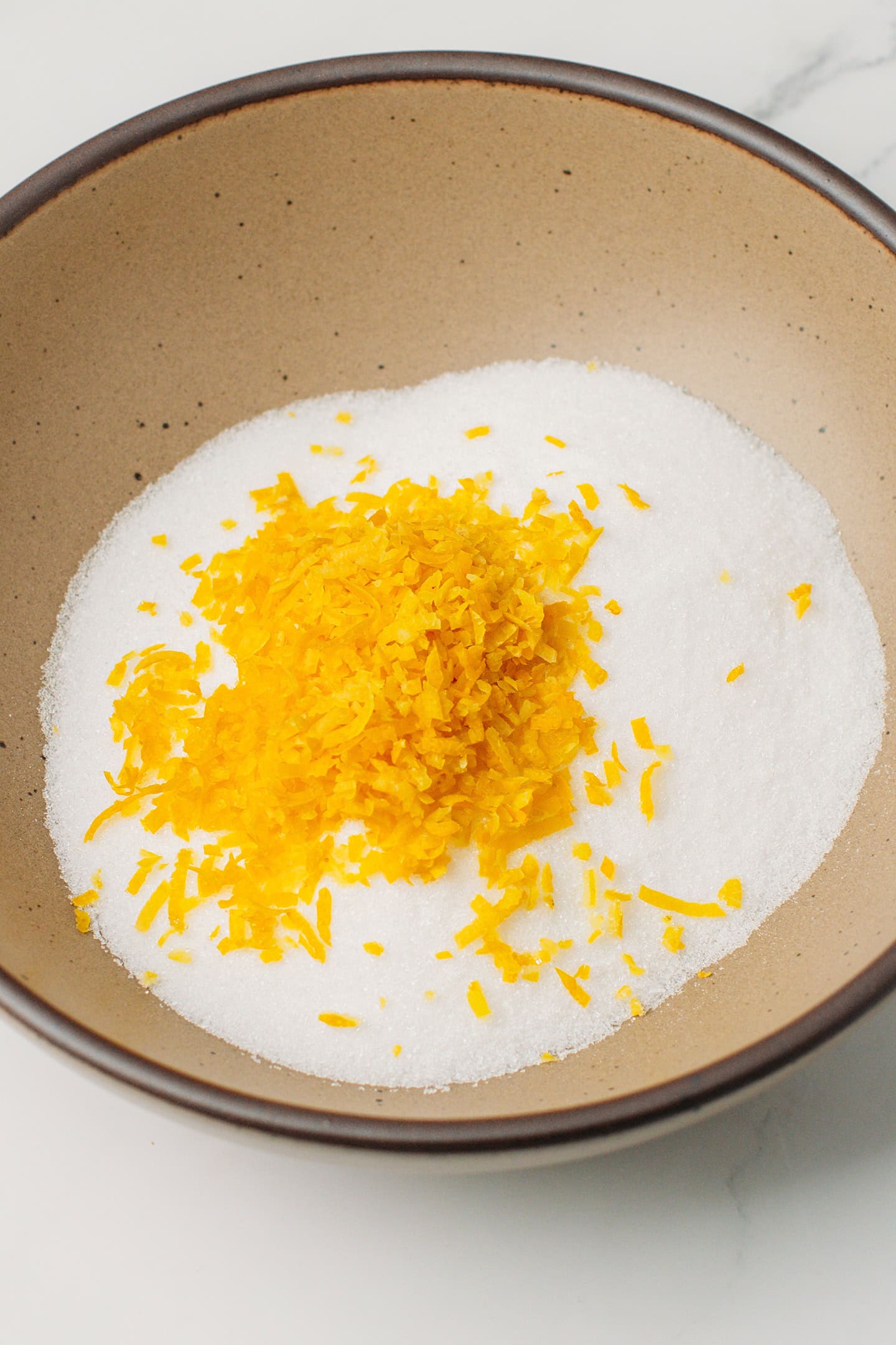 White sugar and lemon zest in a bowl.