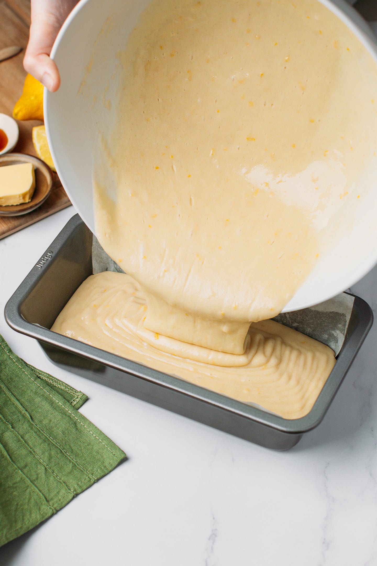 Pouring a lemon batter into a loaf pan.