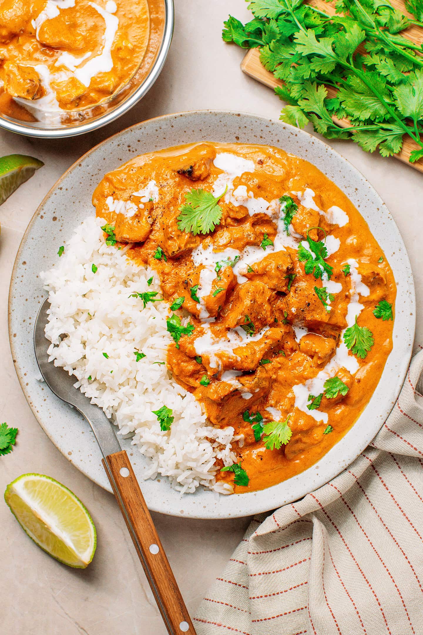 Tofu in a creamy tomato curry sauce with rice and chopped cilantro in a plate.