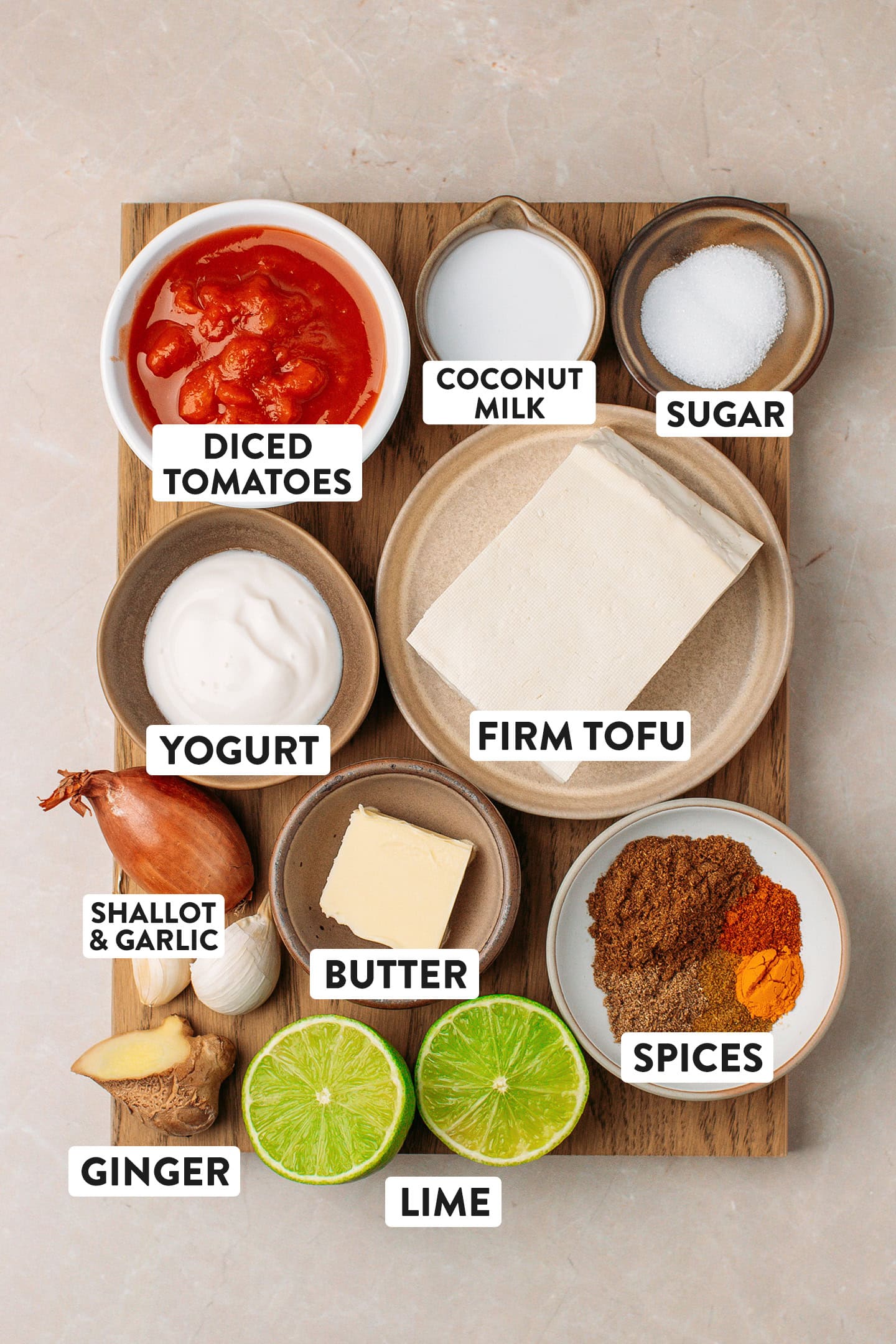 Ingredients like firm tofu, yogurt, spices, vegan butter, and diced tomatoes.