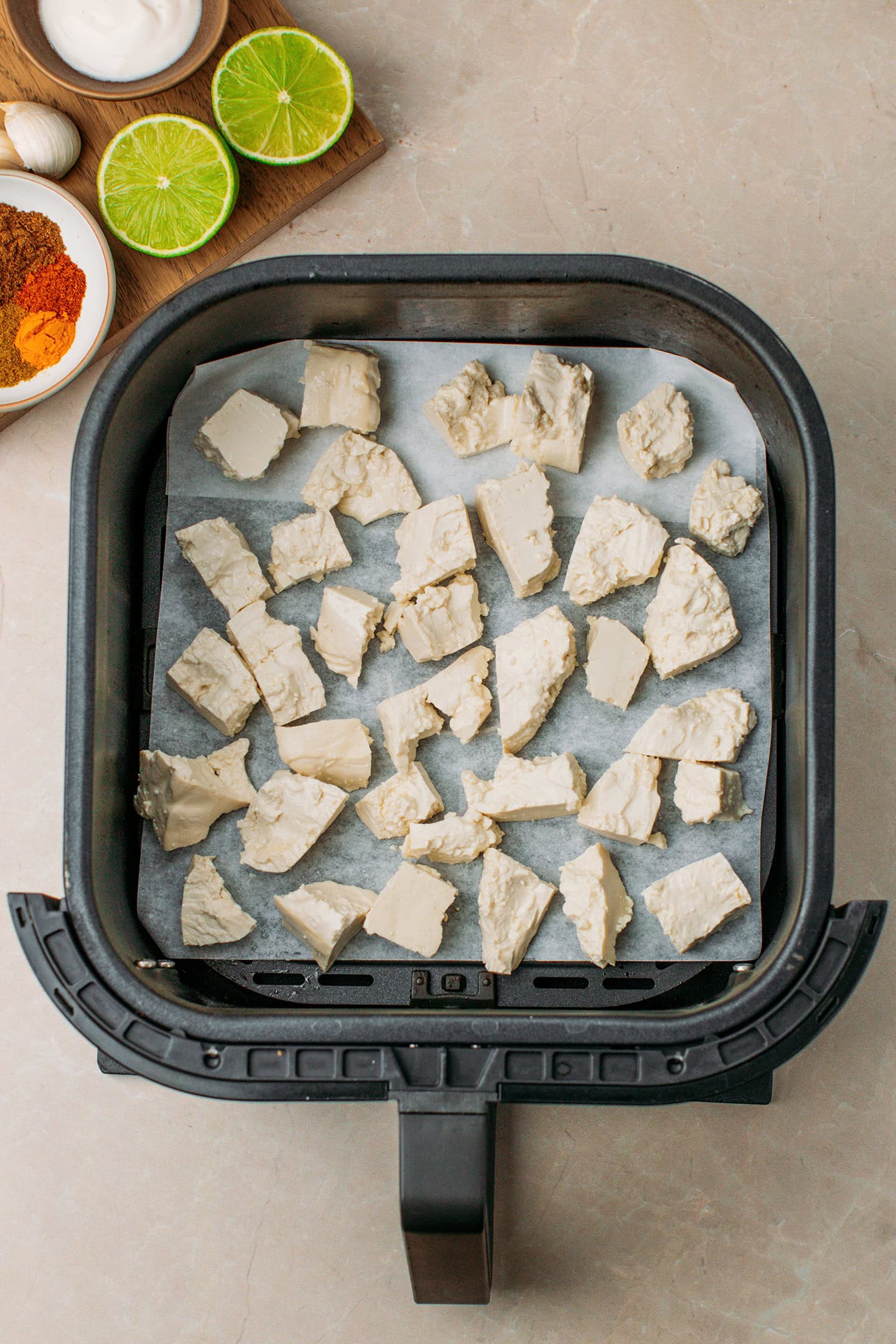 Tofu pieces in an air fryer basket.