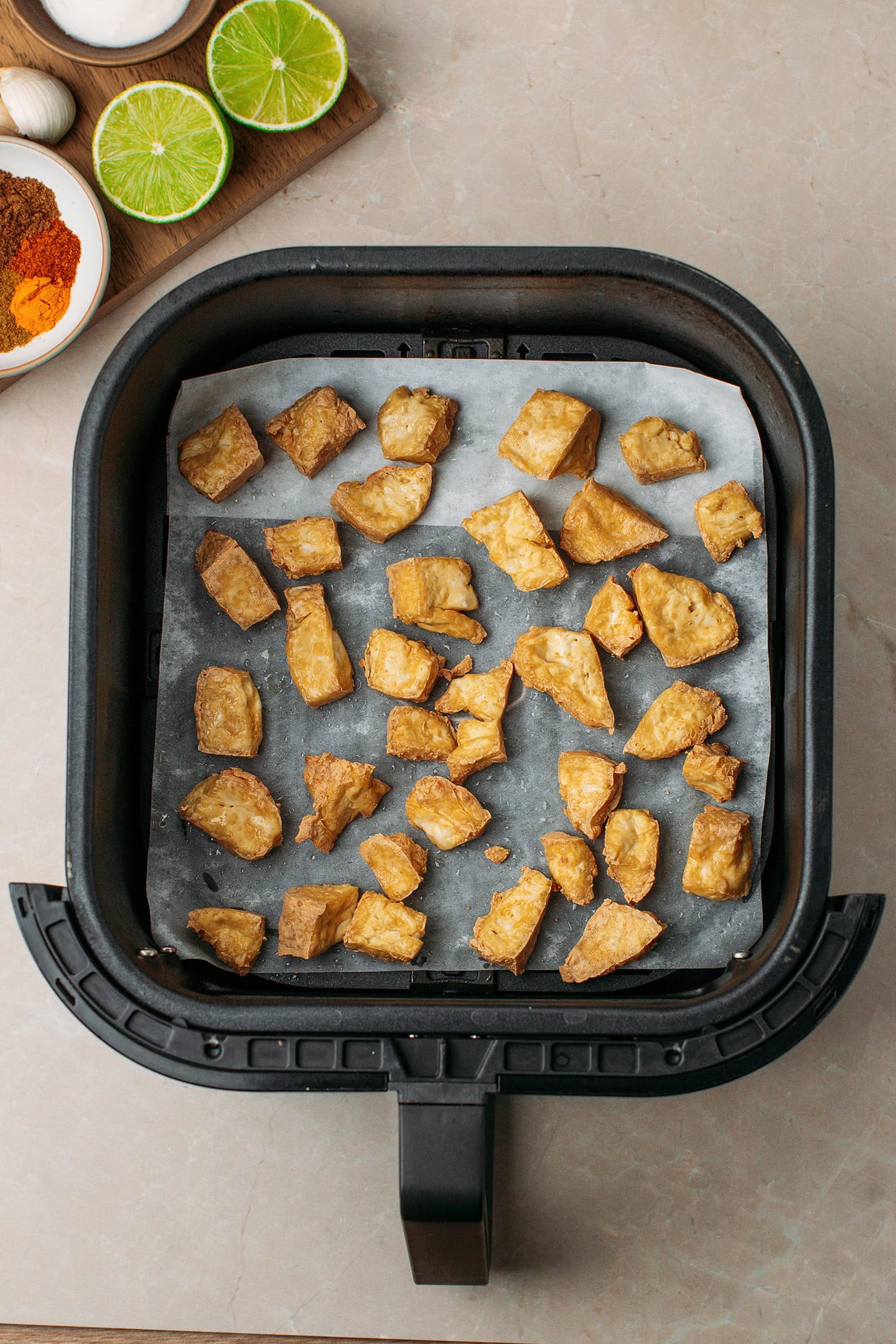 Golden brown tofu pieces in an air fryer basket.