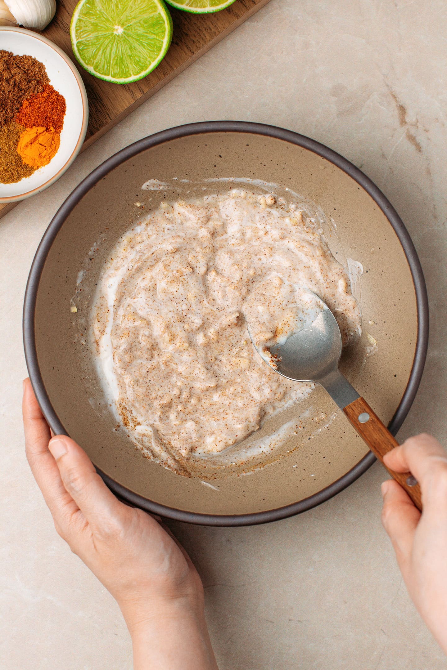 Stirring yogurt, lime juice, and spices in a bowl.