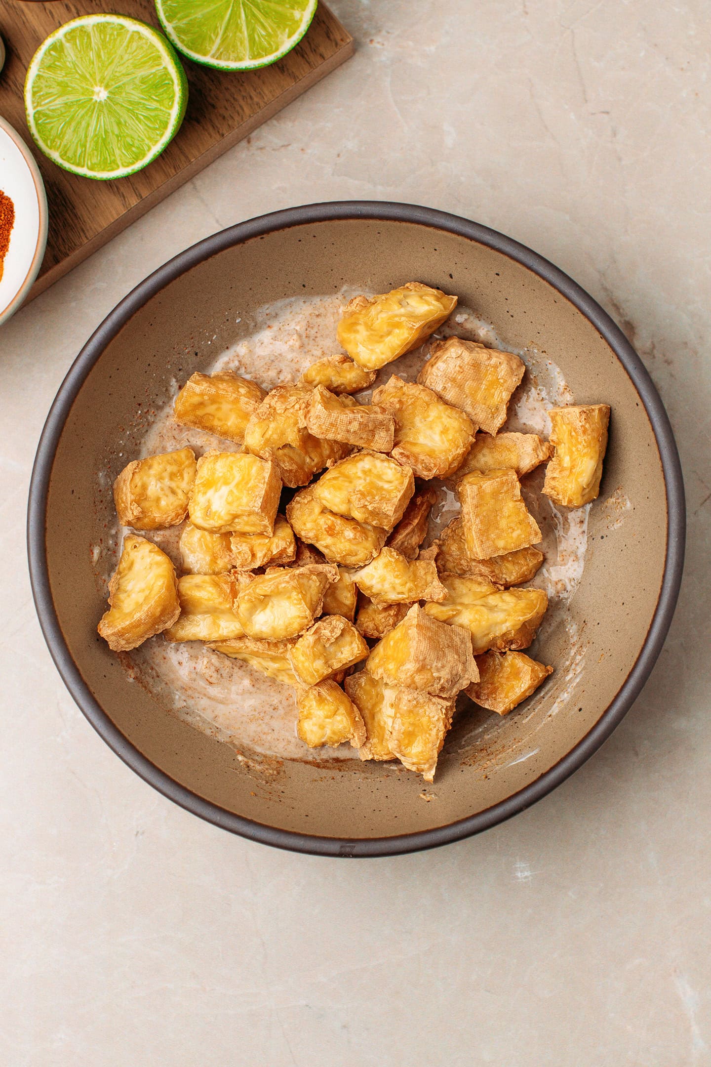 Yogurt marinade and golden brown tofu in a bowl.