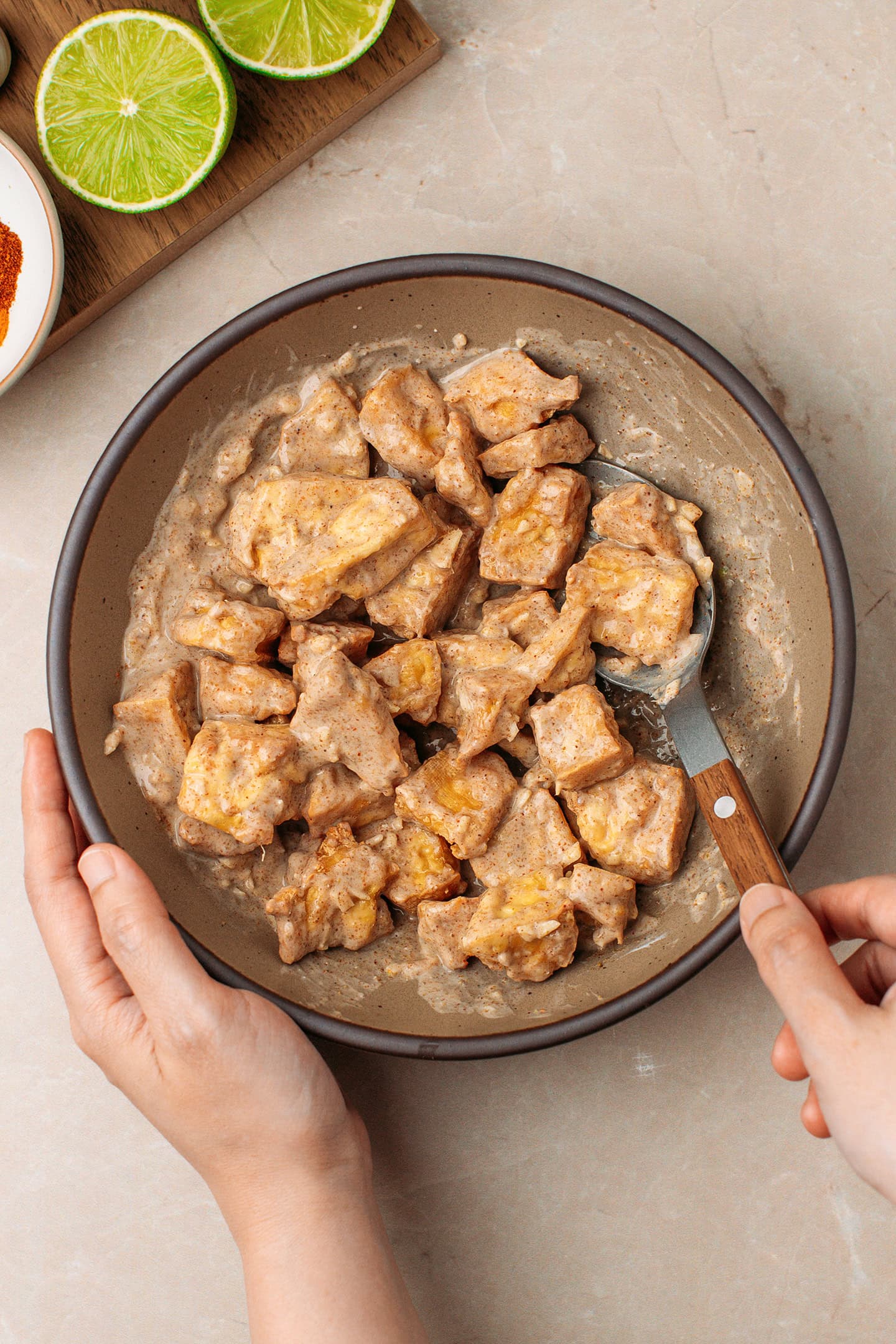 Tossing golden-brown tofu with a yogurt marinated in a bowl.