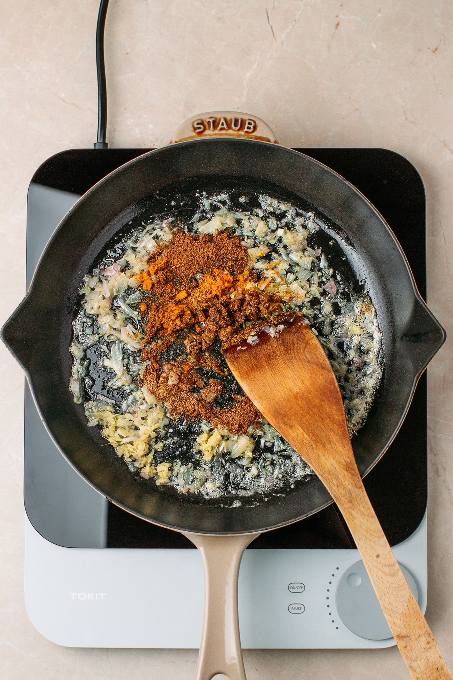 Sautéed garlic, shallot, ginger, and spices in a skillet.