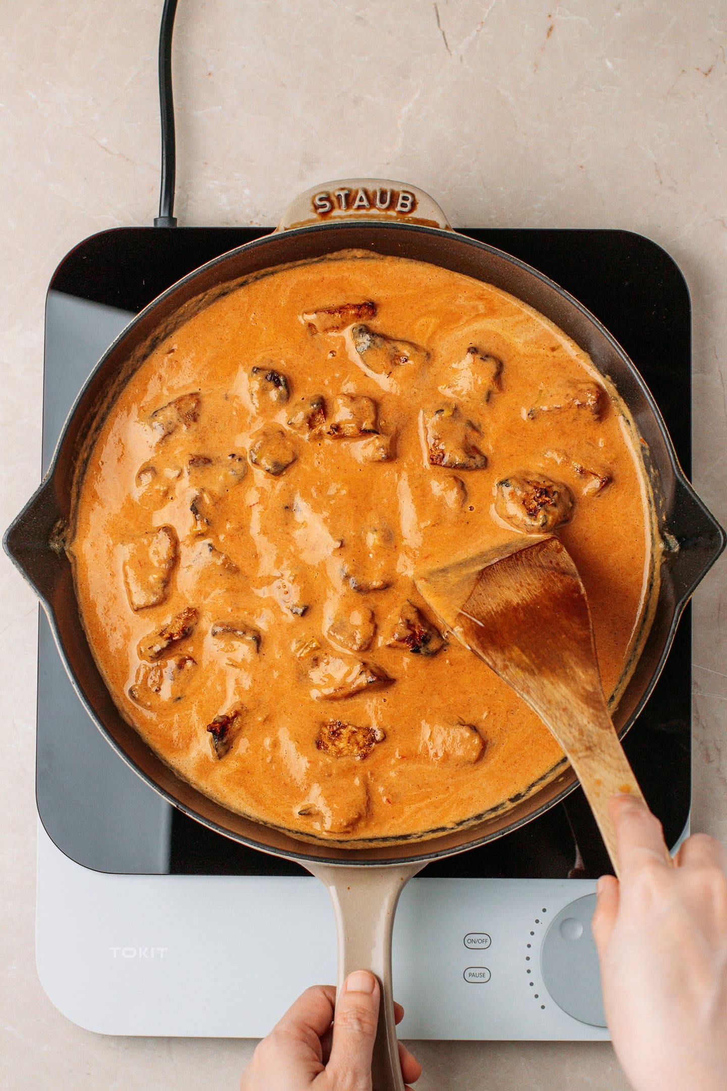 Tossing tofu pieces with a creamy curry sauce in a skillet.
