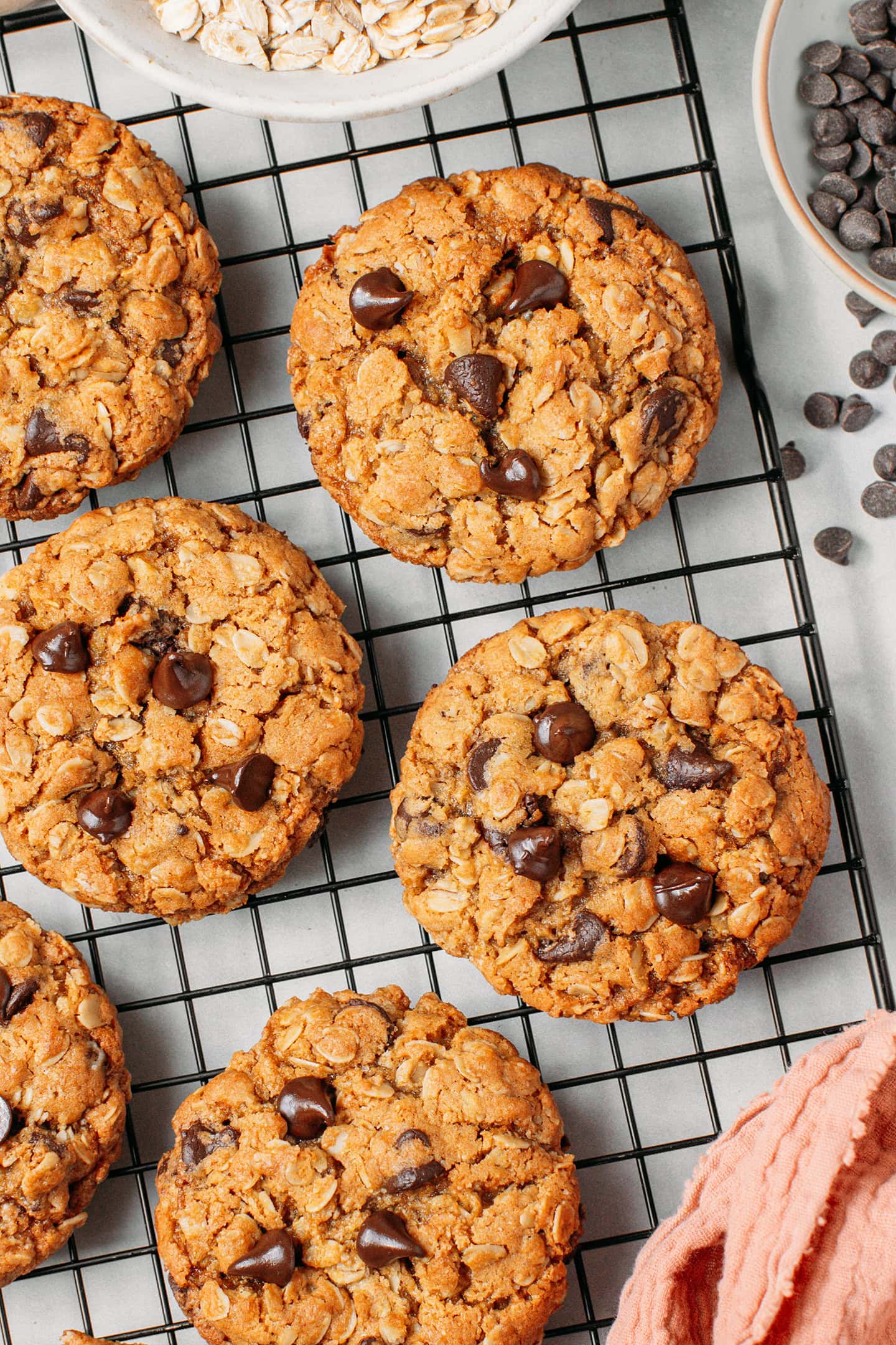 Oatmeal chocolate chip cookies on a black cooling rack.